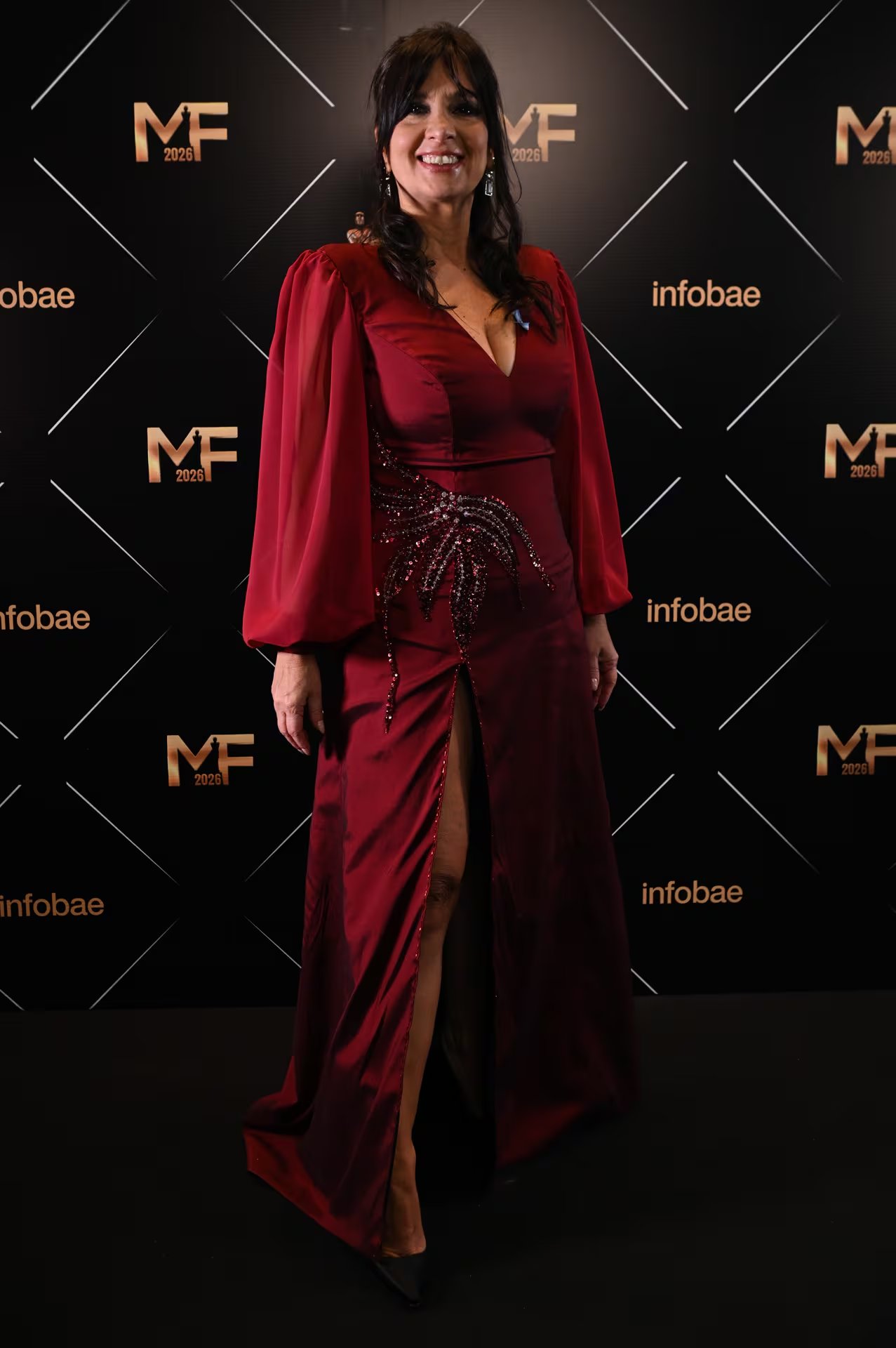 Edith Hermida dijo presente con un vestido largo en tono bordó, de escote pronunciado y mangas largas de gasa. El diseño incorpora un bordado de pedrería en la cadera y una abertura frontal que deja ver las piernas