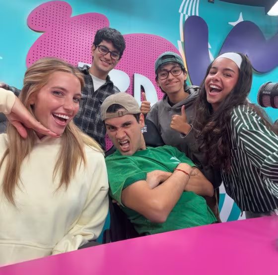 Los integrantes de Zaca TV comparten un momento de alegría y camaradería en su estudio, con expresiones animadas y un ambiente vibrante.