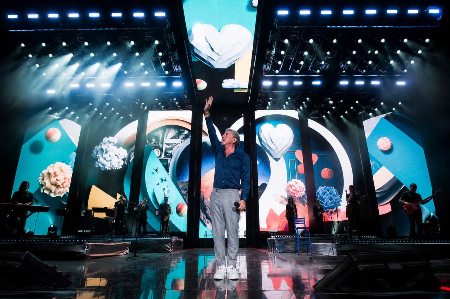 Ricardo Montaner saluda al público en un escenario iluminado con pantallas visuales, enviando un mensaje a los peruanos antes de su esperado concierto el 30 de mayo.