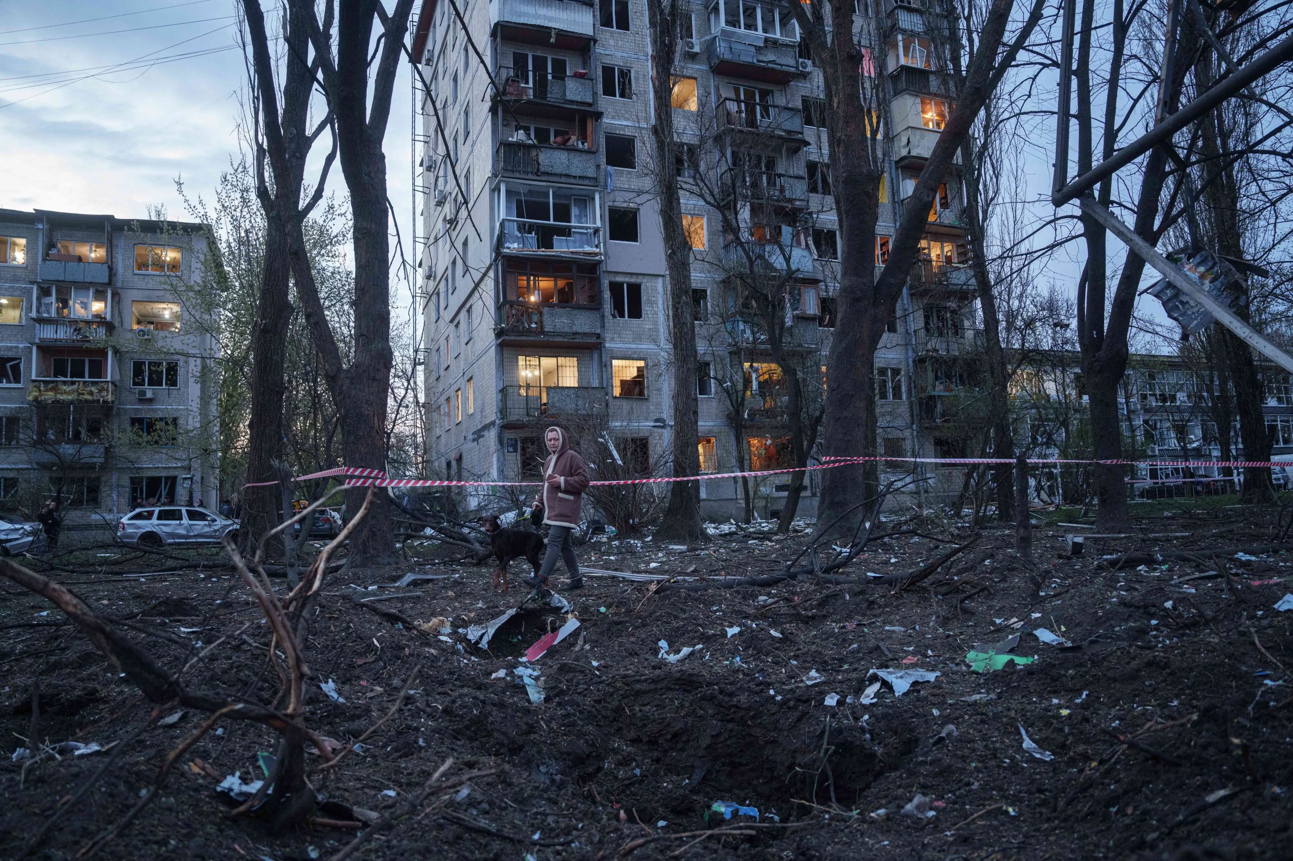 Una mujer con un perro camina entre los escombros de una casa dañada tras un ataque ruso en una zona residencial de Kiev, Ucrania, el jueves 16 de abril de 2026. (AP Photo/Evgeniy Maloletka)