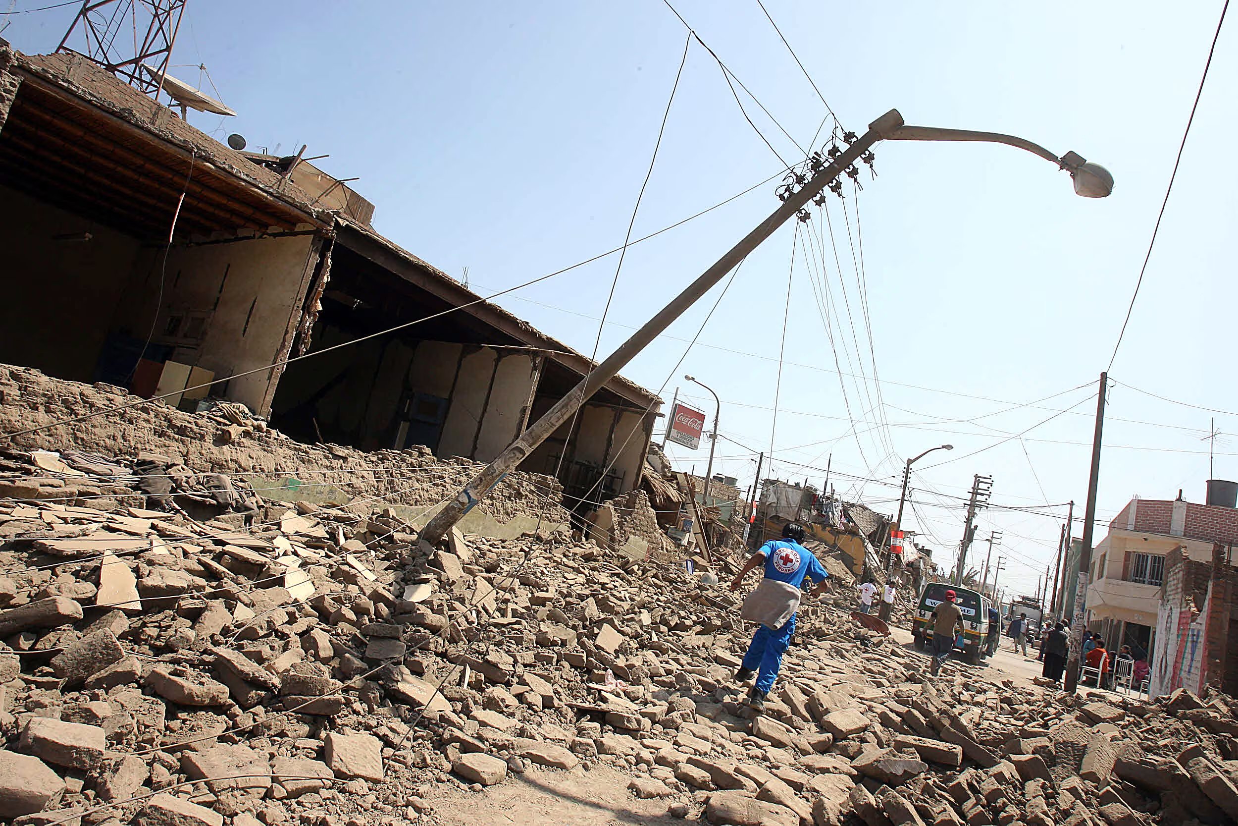 A Peruvian Red Cross member runs amid a devastated street in Pisco, more than 300 km south of Lima, 16 August 2007. Peruvian officials struggled on Thursday to reach cut-off victims on the country's southern coast after a devastating earthquake rocked the region on the eve leaving more than 500 dead and 1,600 injured. AFP PHOTO/Jaime RAZURI (Photo by JAIME RAZURI / AFP)
