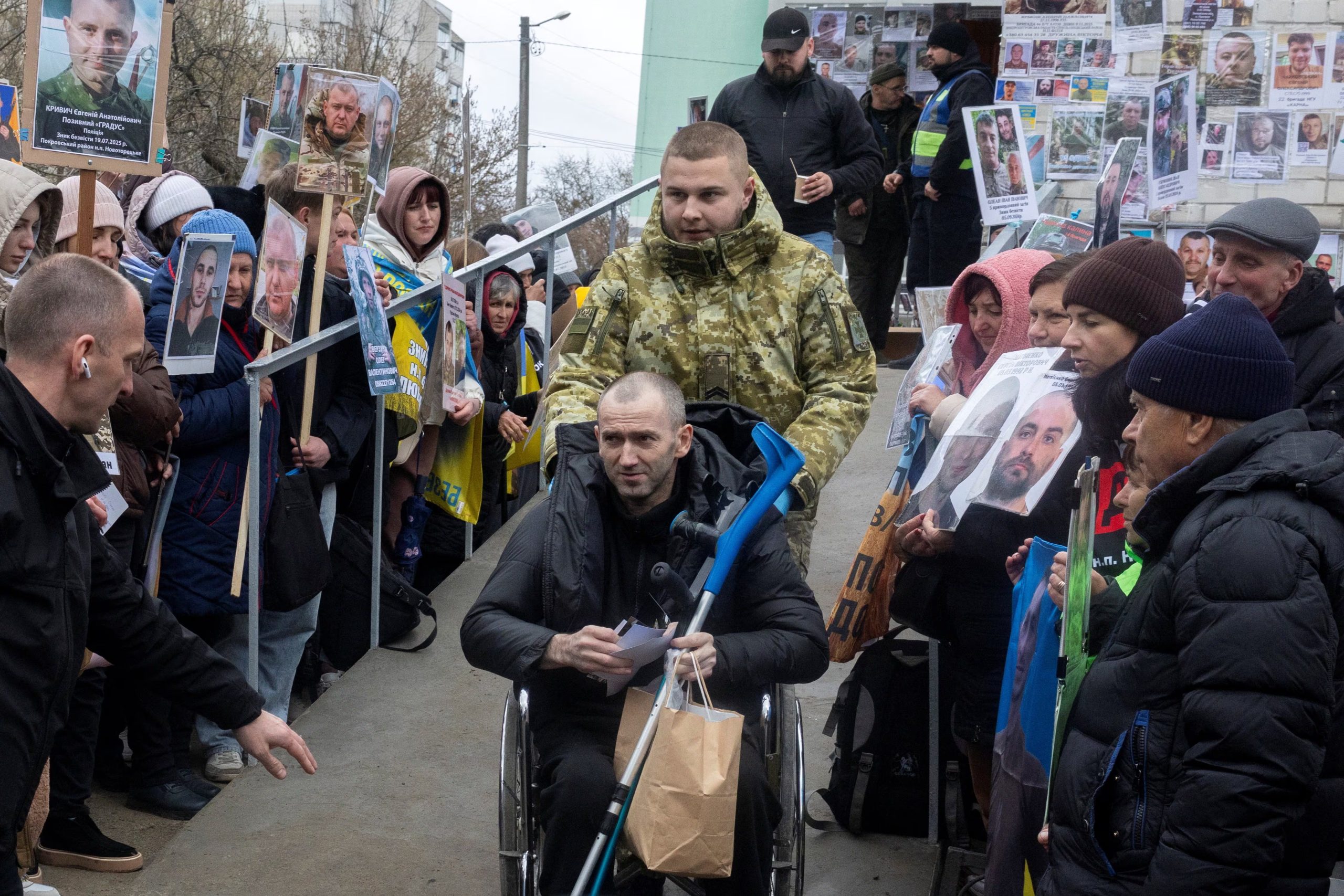 Un prisionero de guerra ucraniano está rodeado de personas que sostienen fotografías de soldados ucranianos desaparecidos a su regreso tras un intercambio de prisioneros, el 11 de abril de 2026 (REUTERS/Thomas Peter)