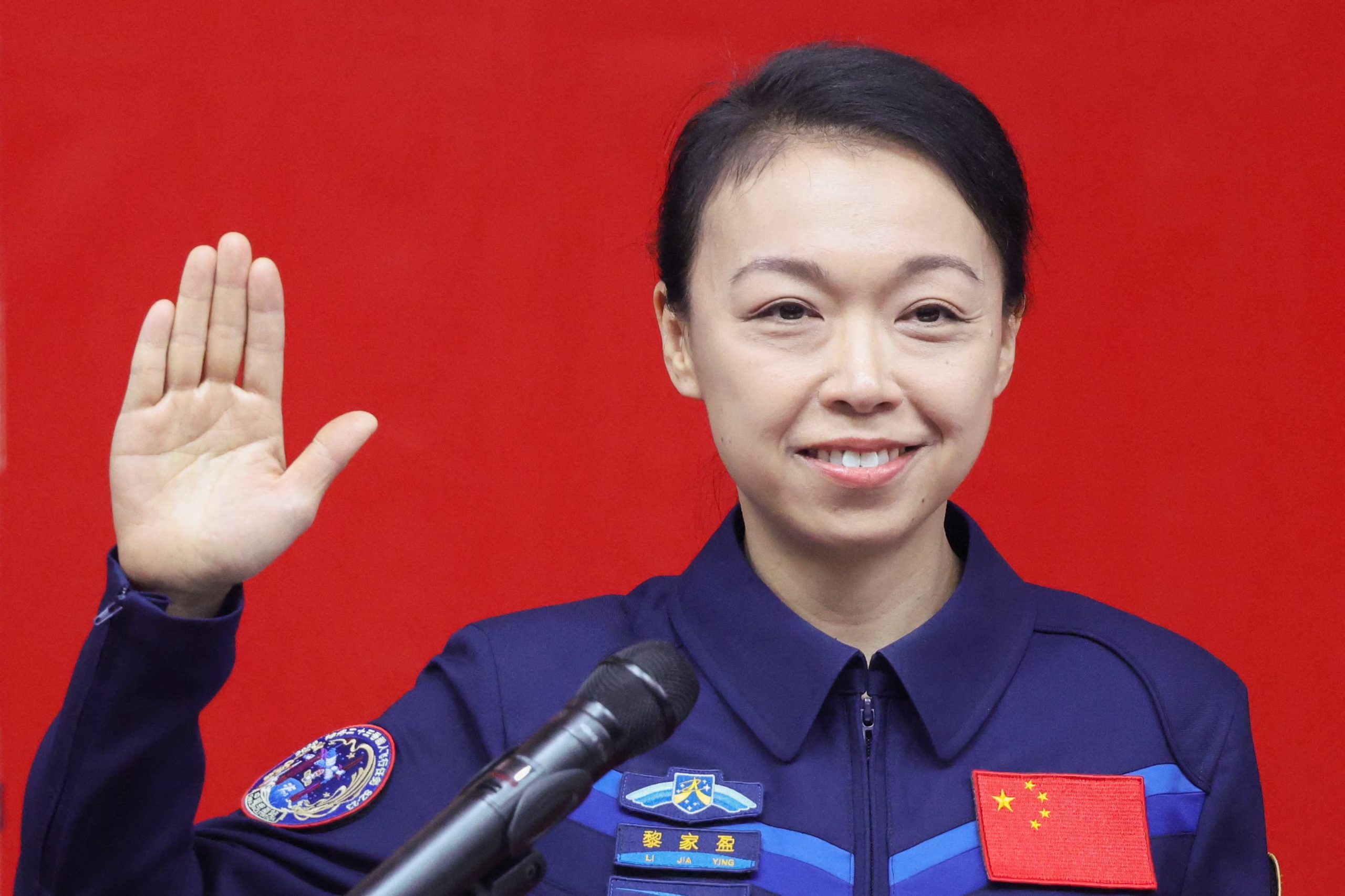 La astronauta Lai Ka-ying, la primera astronauta de Hong Kong, levanta la mano mientras asiste a una conferencia de prensa con sus compañeros de tripulación Zhu Yangzhu y Zhang Zhiyuan. (REUTERS/Maxim Shemetov)