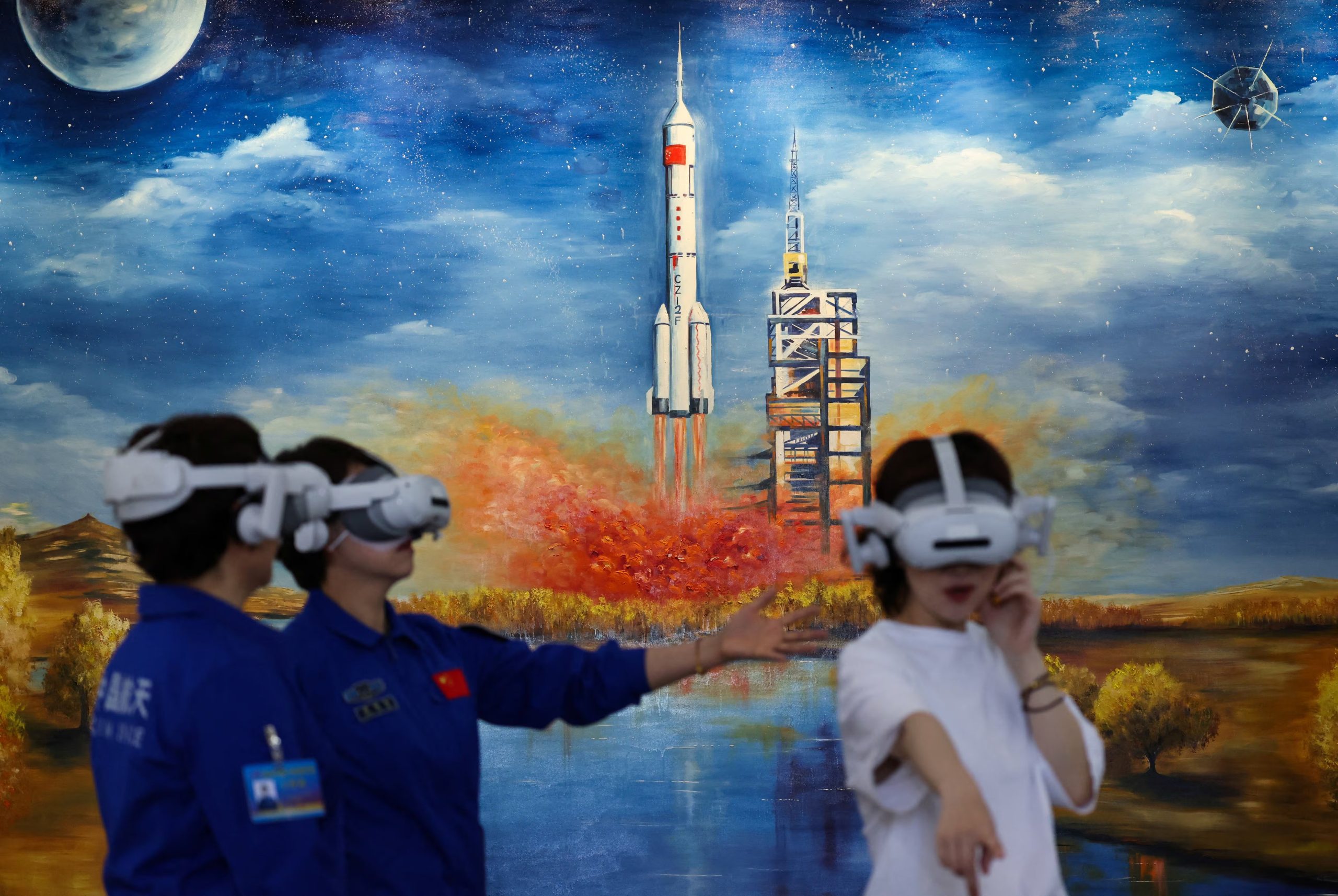 Técnicos de la agencia espacial china utilizan visores de realidad virtual junto a un mural del cohete Larga Marcha 2F en Jiuquan, víspera del lanzamiento de la misión Shenzhou-23 hacia la estación Tiangong. (REUTERS/Maxim Shemetov)