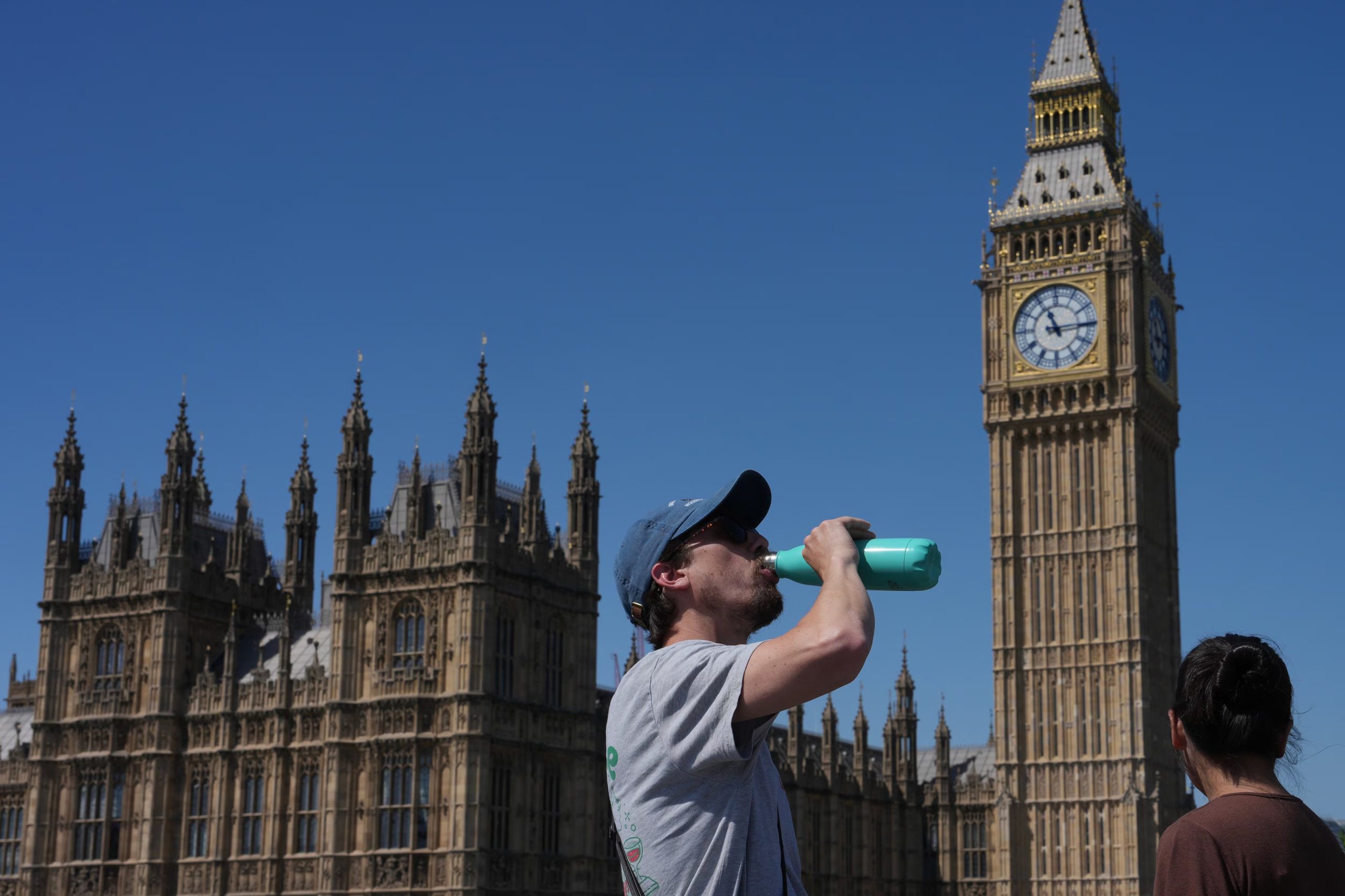 Un hombre se hidrata frente al Palacio de Westminster, sede del Parlamento británico, durante la jornada en que Londres registró su temperatura más alta en un mes de mayo desde que hay registros. (AP Photo/Kin Cheung)