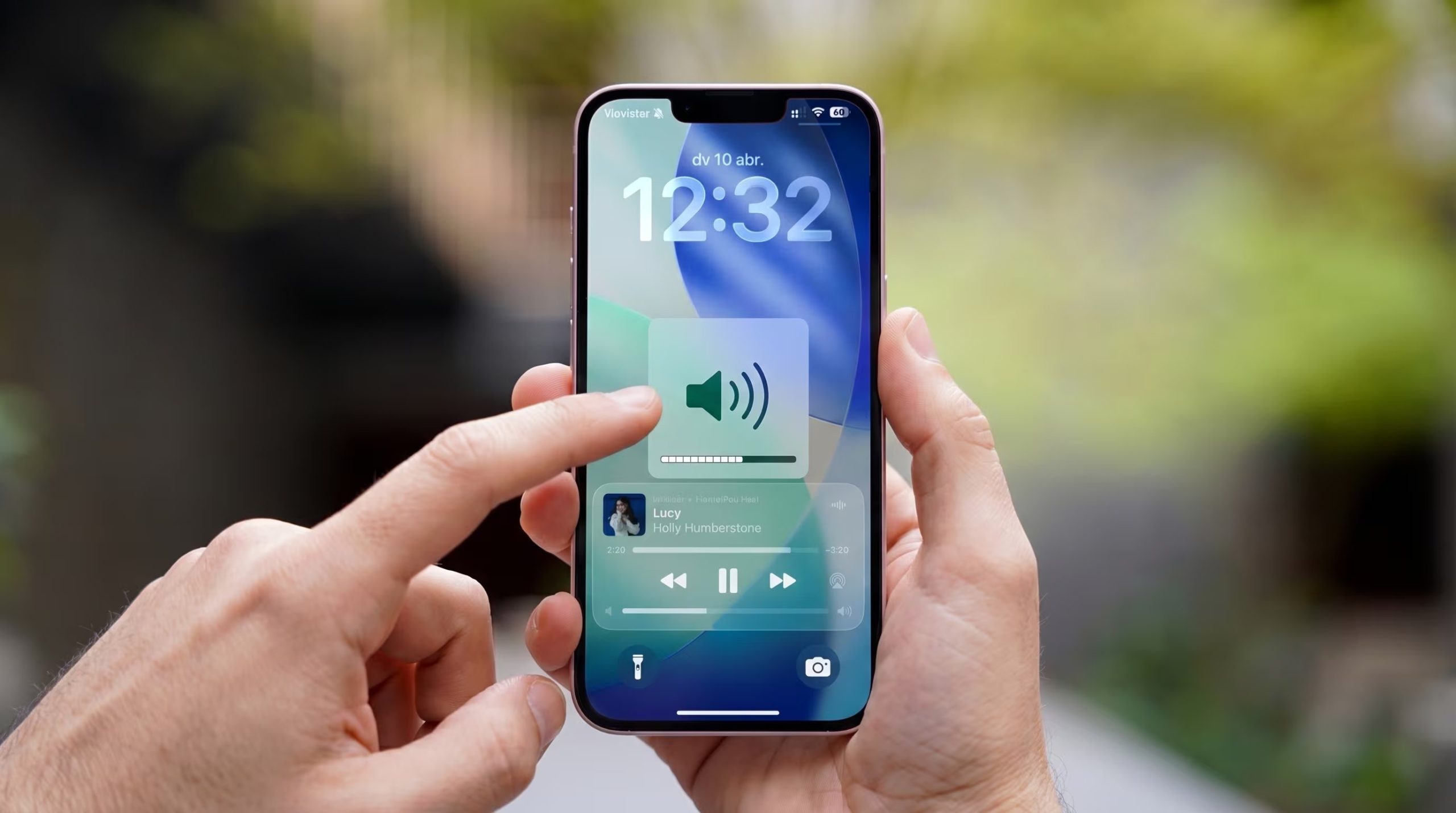 Una persona ajusta el volumen y controla la reproducción musical de un iPhone de color rosa/morado desde la pantalla de bloqueo, mostrando la interfaz del dispositivo. (Imagen Ilustrativa Infobae)