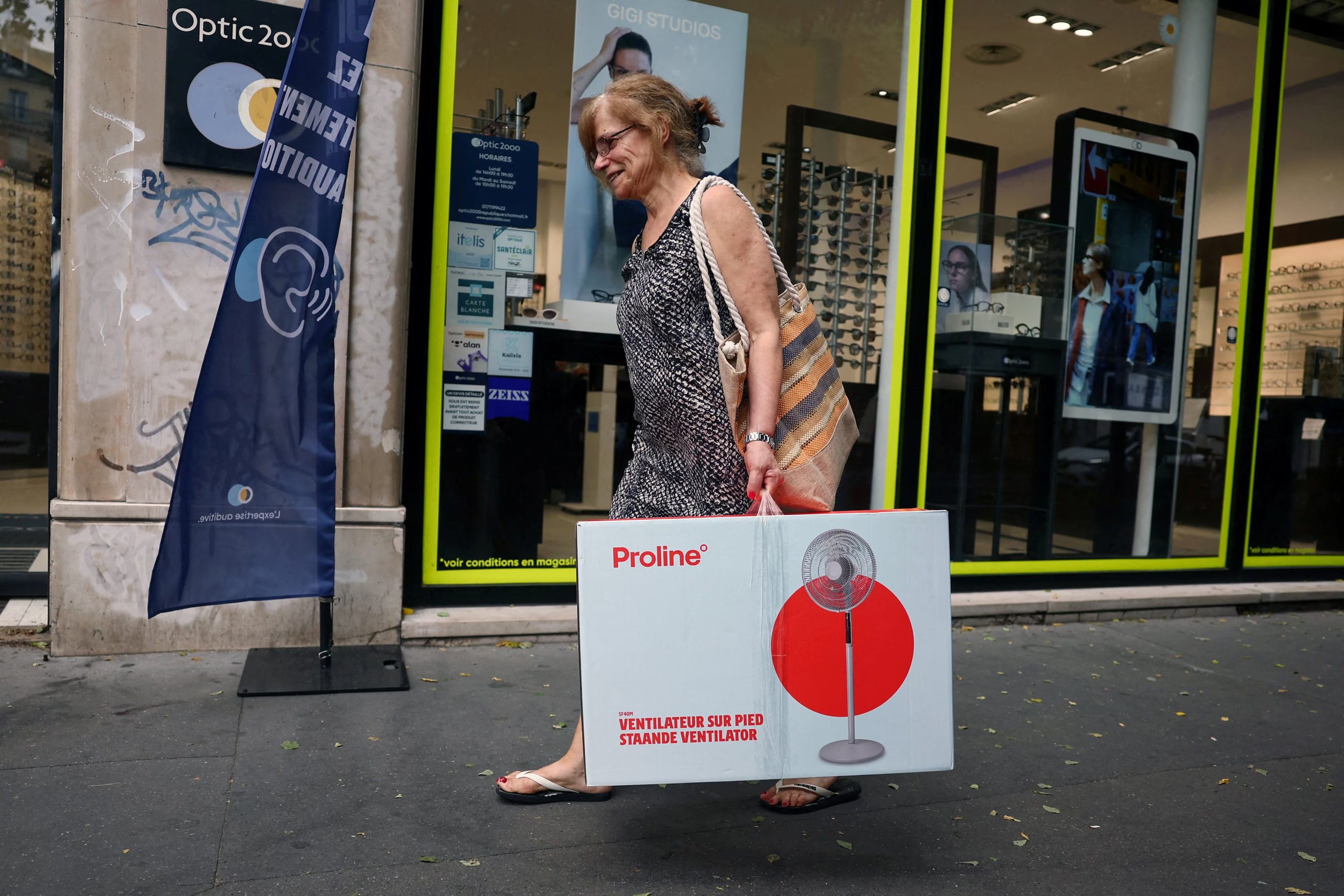 Una mujer que lleva un ventilador eléctrico en una caja de cartón camina por una calle mientras suben las temperaturas en París durante una ola de calor que afecta a gran parte de Francia, el 23 de junio de 2026. REUTERS/Abdul Saboor