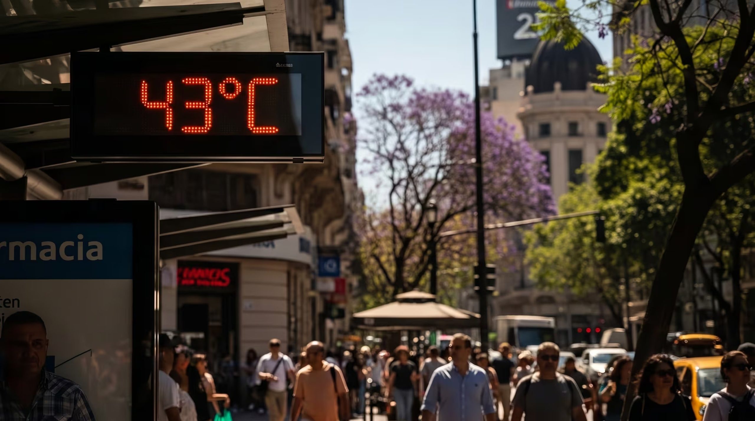 Un termómetro digital marca 43 grados Celsius en una calle concurrida, bajo un cielo despejado que indica un día caluroso para los transeúntes