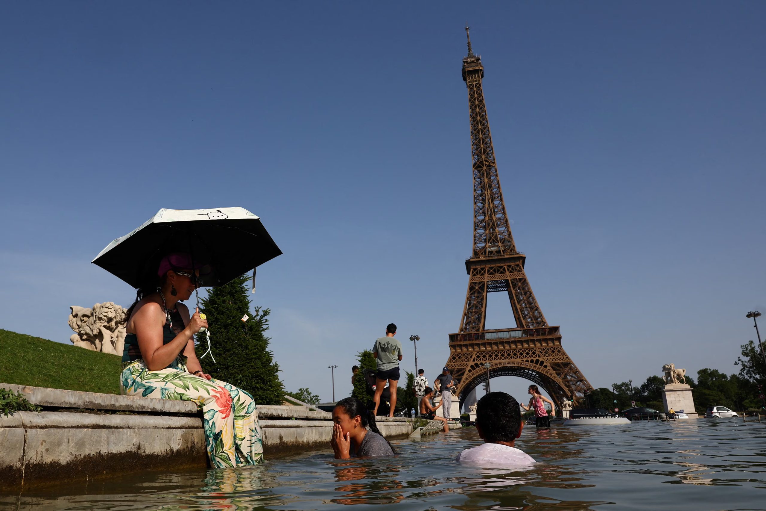 La gente se refresca en la fuente del Trocadero, frente a la Torre Eiffel, mientras las temperaturas suben en París durante una ola de calor que afecta a gran parte de Francia, 23 de junio de 2026. REUTERS/Abdul Saboor