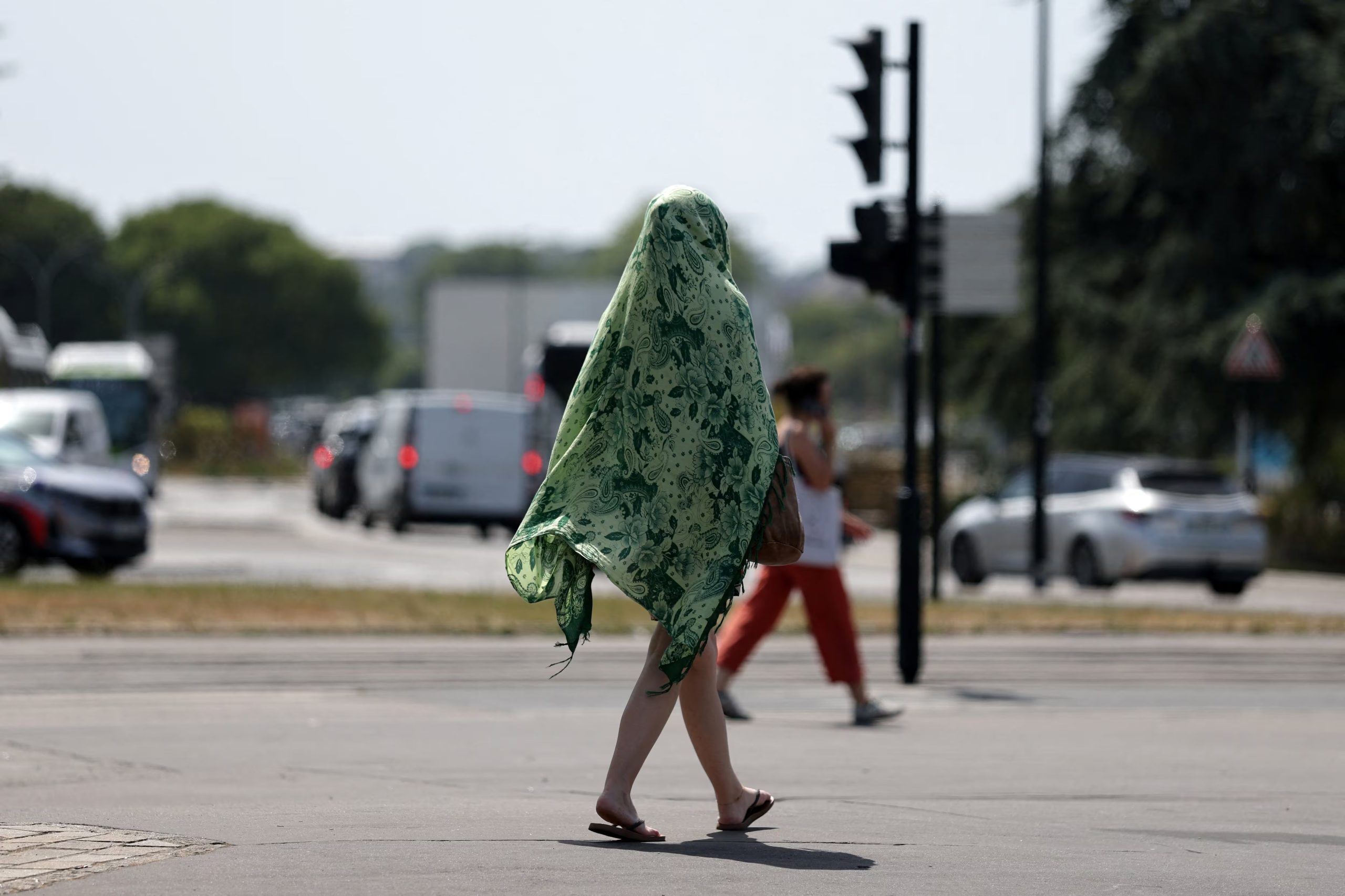Una persona con un chal sobre la cabeza y el cuerpo para protegerse del sol camina por una calle mientras las temperaturas suben en Nantes durante una ola de calor que afecta a gran parte de Francia, 23 de junio de 2026. REUTERS/Stephane Mahe