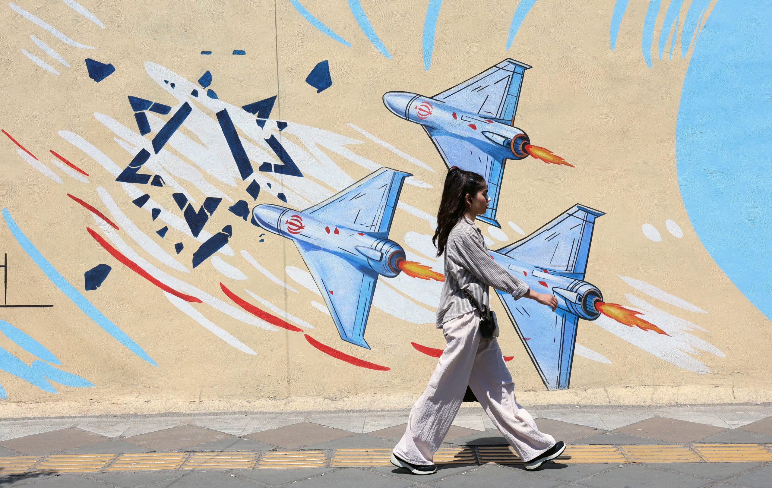 Una joven iraní pasa junto a un mural antiisraelí en una calle de Teherán, Irán, el lunes 8 de junio (EFE)