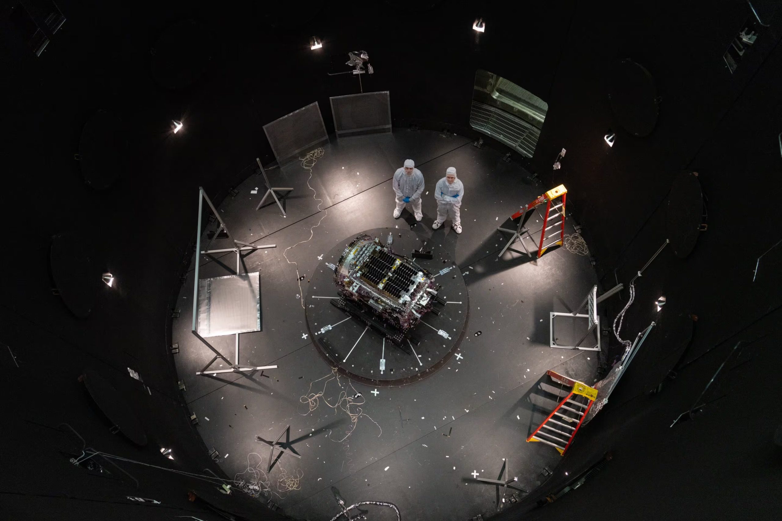 Esta fotografía, proporcionada por la NASA, muestra a Kieran Wilson, investigador principal de LINK, y a Hunter Robertson, ingeniero de sistemas espaciales, ambos de Katalyst Space, junto a su nave espacial dentro del SES (Simulador de Entorno Espacial) en el Centro de Vuelos Espaciales Goddard de la NASA en Greenbelt, Maryland, antes de las pruebas de vacío térmico (NASA)