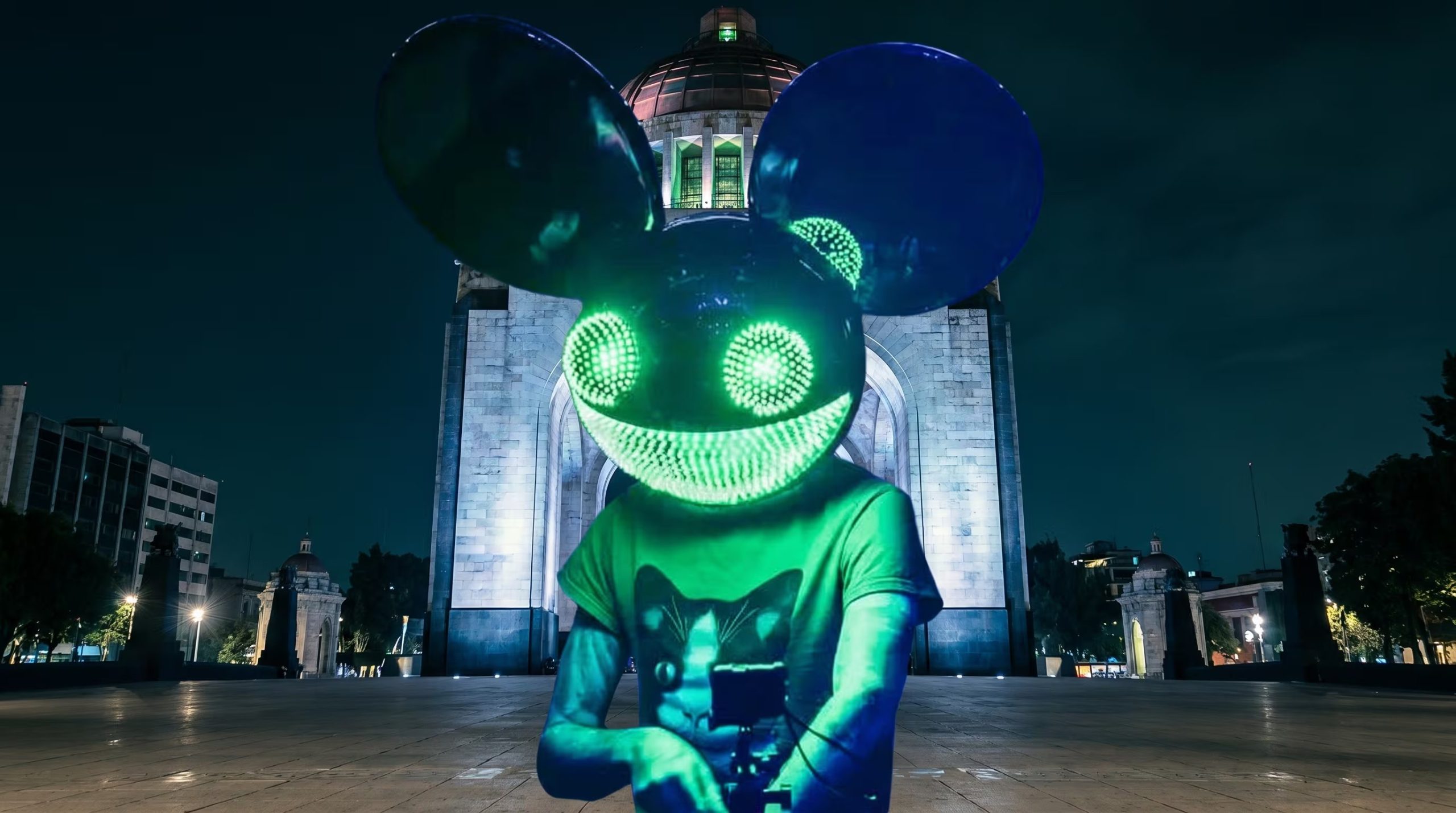 Una figura con una máscara luminosa al estilo de Deadmau5 y ojos verdes brillantes posa frente al icónico Monumento a la Revolución en la Ciudad de México durante la noche, creando una escena vibrante. (Imagen Ilustrativa Infobae)