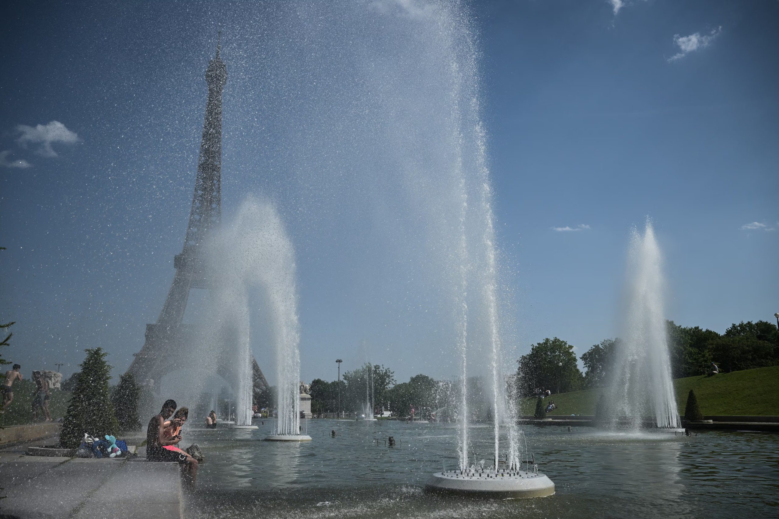 Personas se refrescan en la fuente del Trocadero frente a la Torre Eiffel durante la ola de calor en Francia. (Julien de Rosa/AFP)