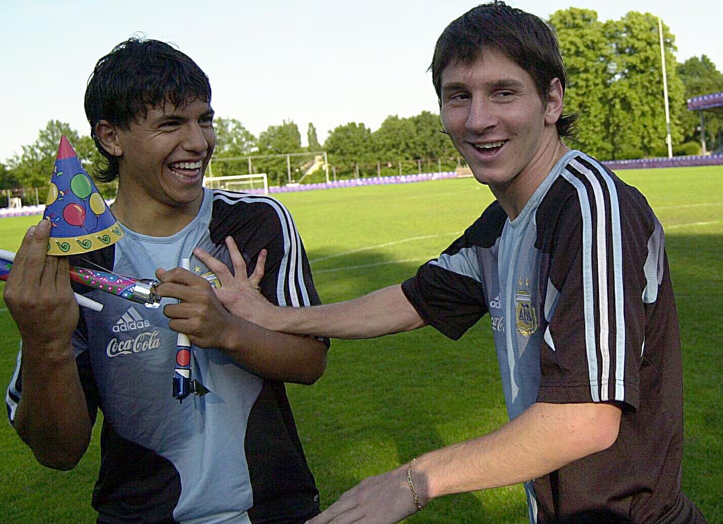 Sergio Agüero y Lionel Messi sonríen mientras Agüero sostiene un gorro de fiesta y un cotillón durante el cumpleaños de Messi en el Mundial Sub-20 de 2005. (Fotobaires)
