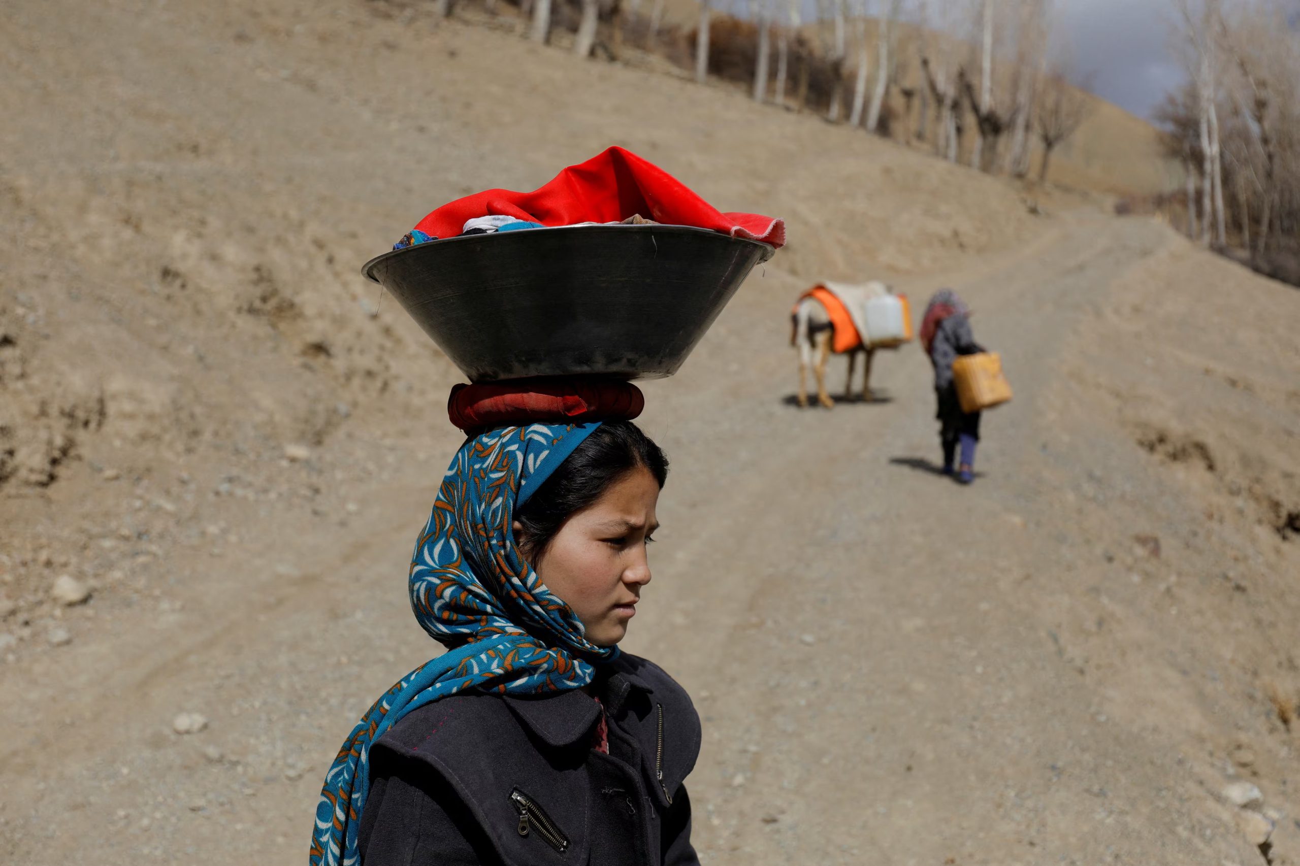 Una niña afgana transporta ropa lavada sobre su cabeza en la provincia de Bamiyán (REUTERS/Ali Khara/archivo)