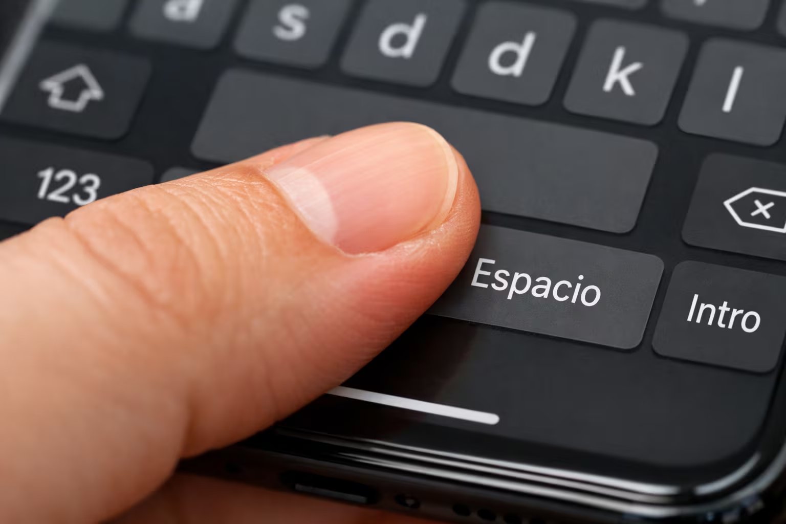 Un primer plano muestra el dedo de una persona presionando la barra espaciadora de un teclado virtual en la pantalla de un teléfono celular. (Imagen Ilustrativa Infobae)