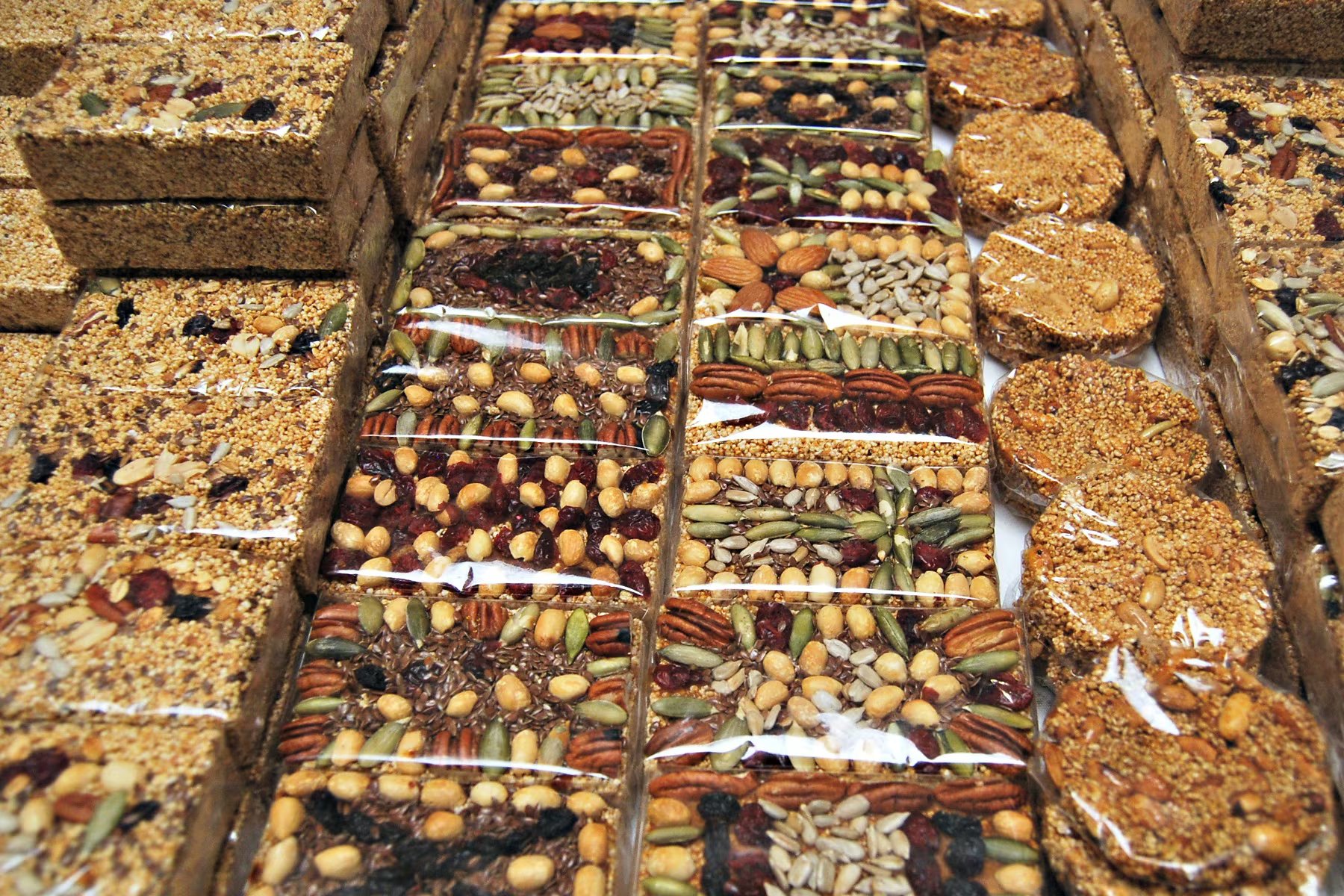 Una colección de dulces y barras de amaranto, decorados con diversas semillas y frutos secos, se exhibe envuelta en plástico. (Secretaría de Agricultura)