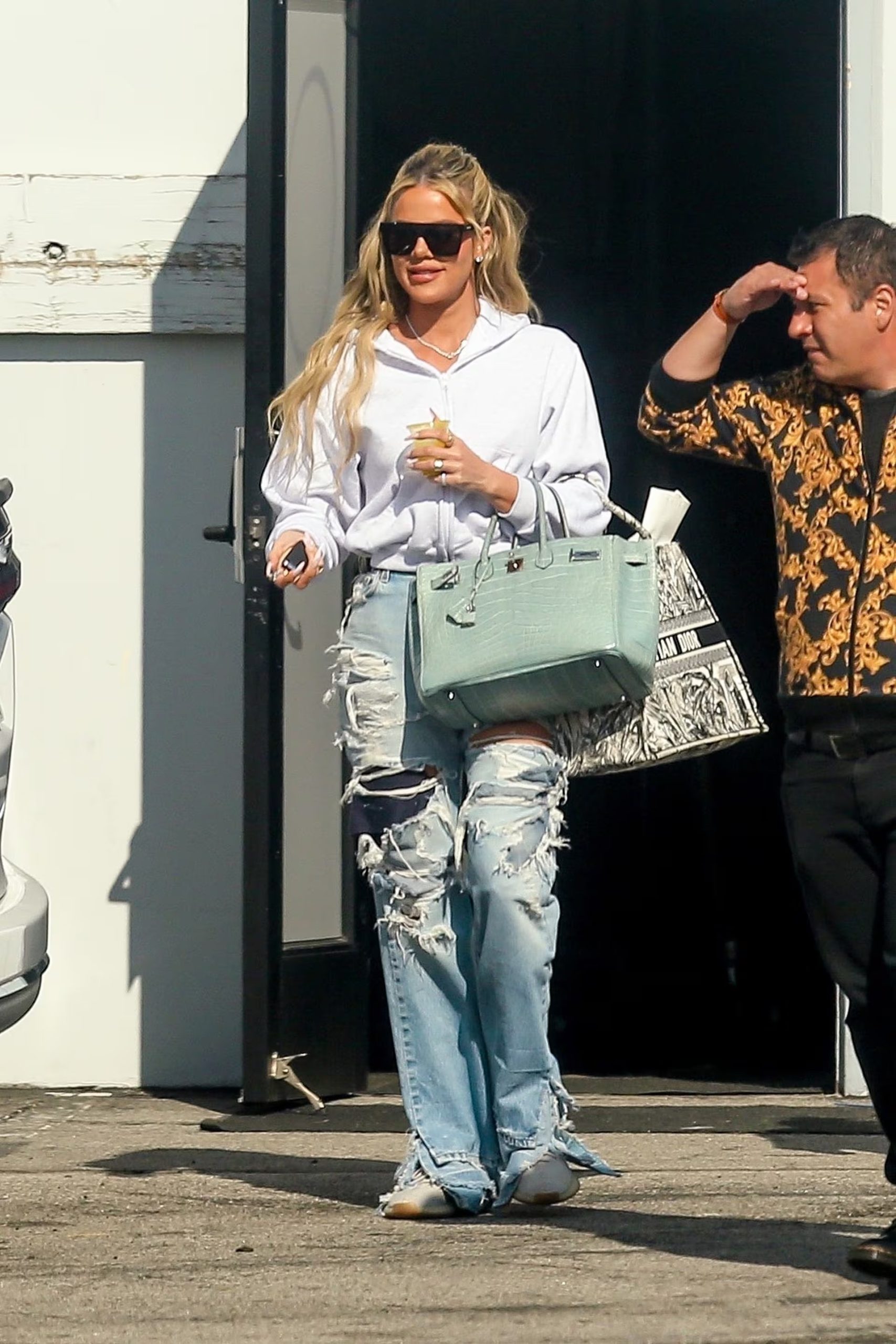 En un look relajado y street, Khloe lució una sudadera blanca holgada con jeans (Backgrid)