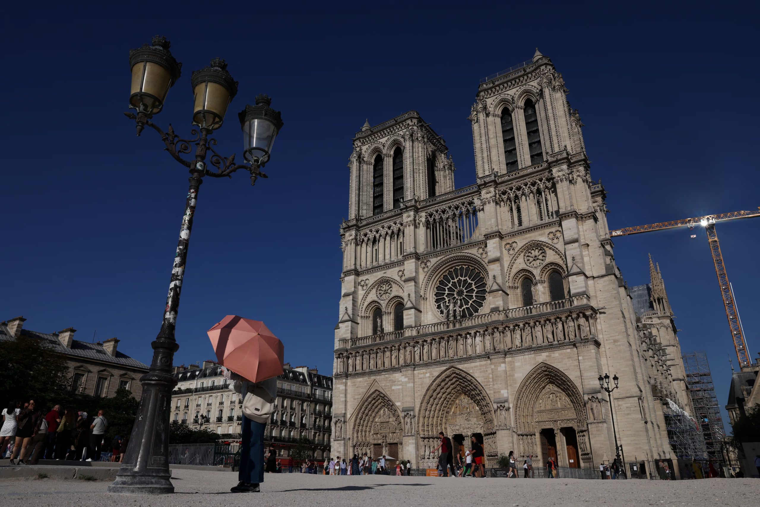 Una persona se refugia bajo un paraguas frente a la catedral de Notre Dame. La remodelación de la explanada, prevista para 2028, incorporará 160 árboles para dar sombra a los visitantes en los cada vez más calurosos veranos parisinos. (REUTERS/Tom Nicholson)