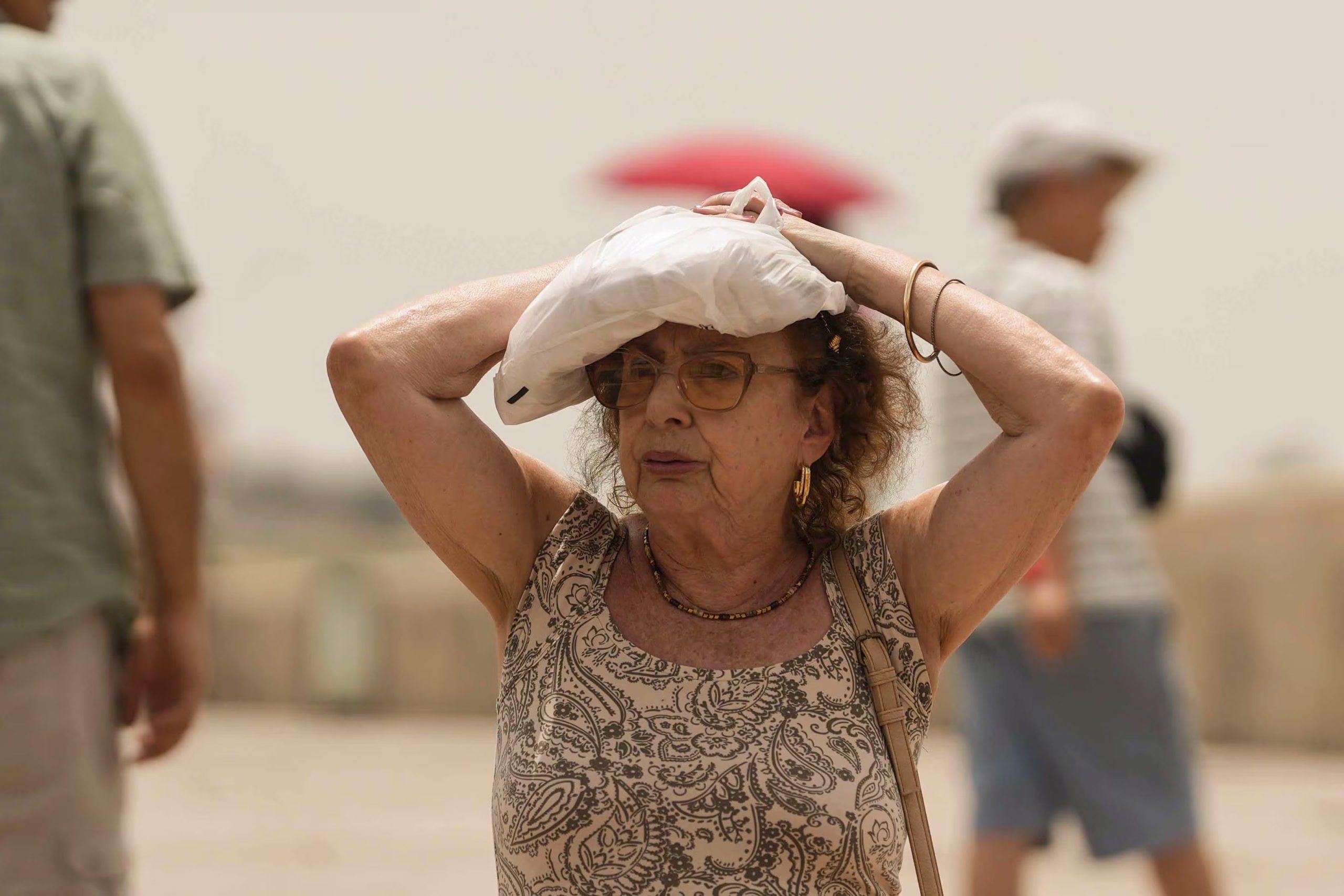 Un turista se protege del sol mientras cruza el Puente Romano de Córdoba, a 23 de junio de 2026. (EFE/Rafa Alcaide)