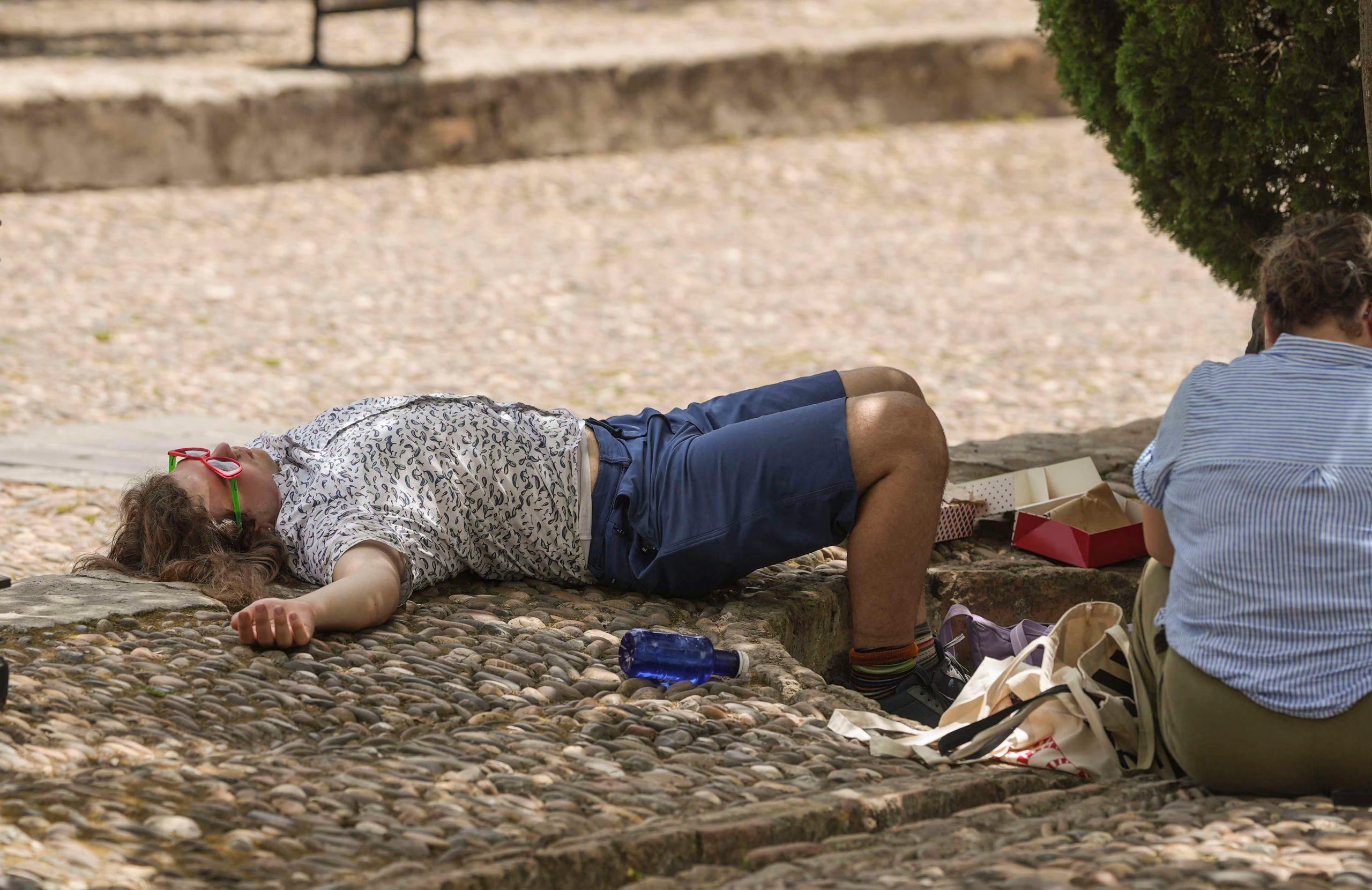Un turista descansa a la sombra de un árbol en el Patio de los Naranjos, en Córdoba, a 23 de junio de 2026. (EFE/Rafa Alcaide)