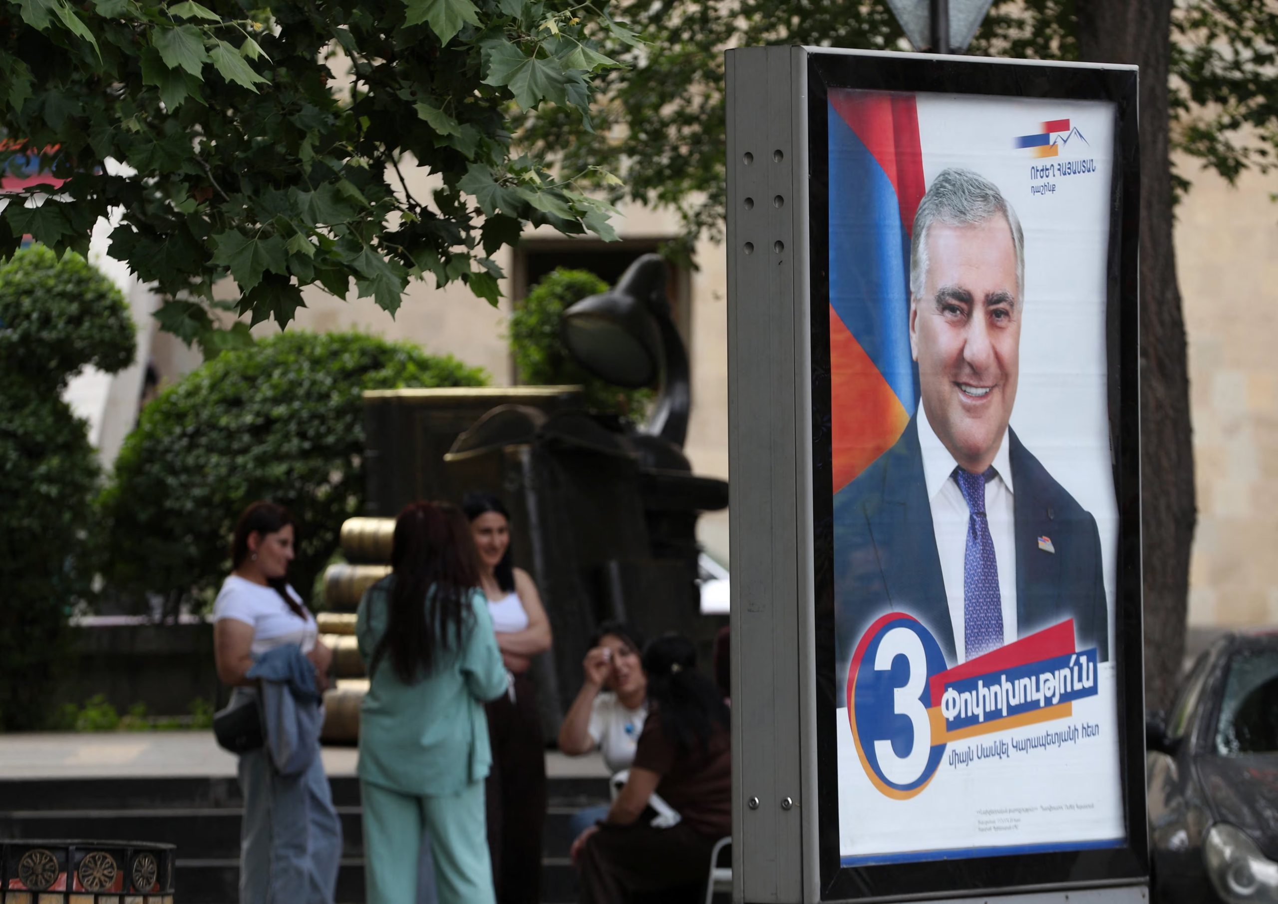 Varias personas posan junto a una pancarta de campaña del partido Armenia Fuerte, liderado por Samvel Karapetyan, antes de las elecciones parlamentarias del 7 de junio en Ereván, Armenia, el 2 de junio de 2026 (REUTERS)
