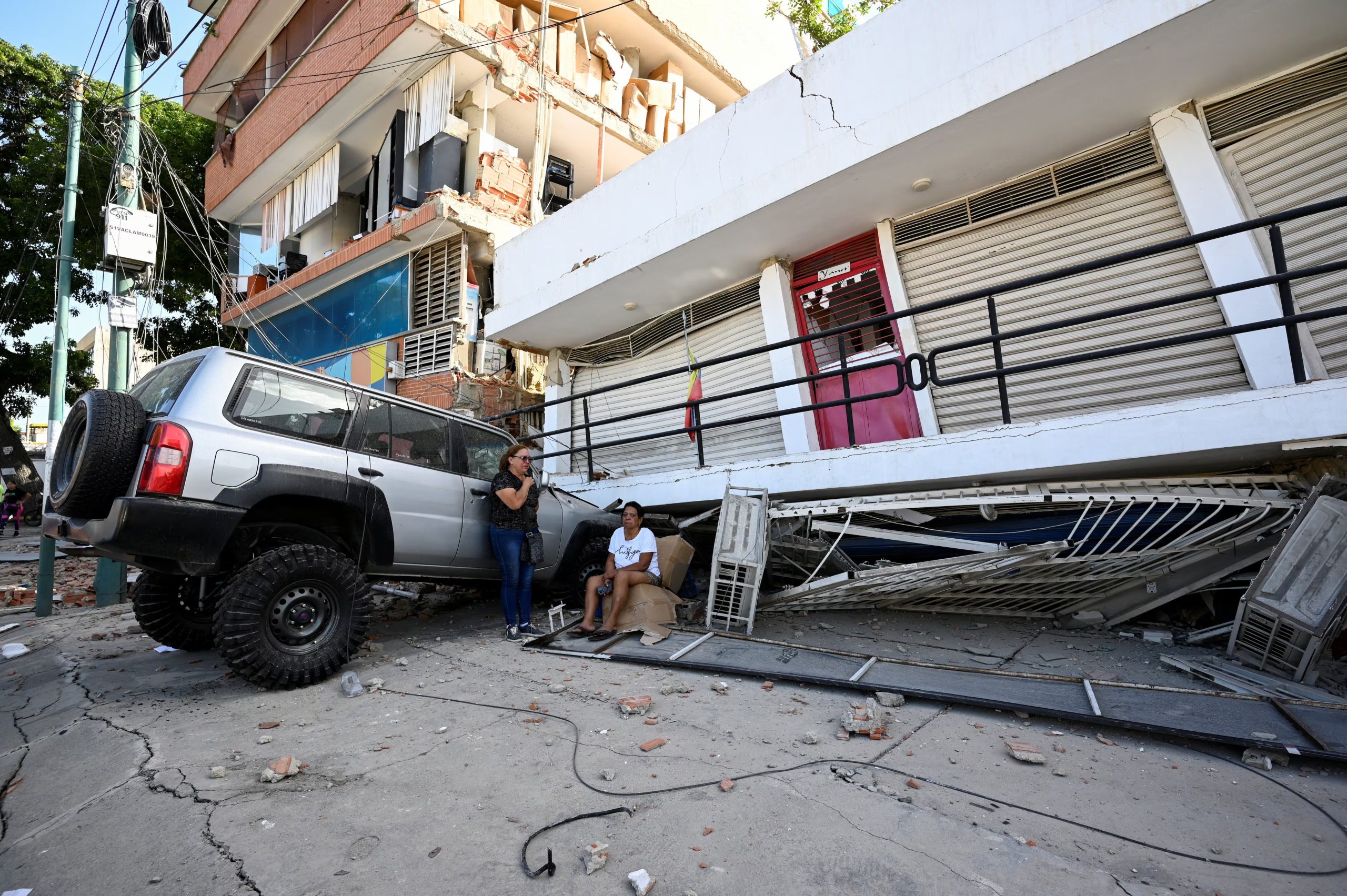 Personas se refugian cerca de un vehículo averiado y un edificio colapsado tras los fuertes terremotos en Venezuela (REUTERS)