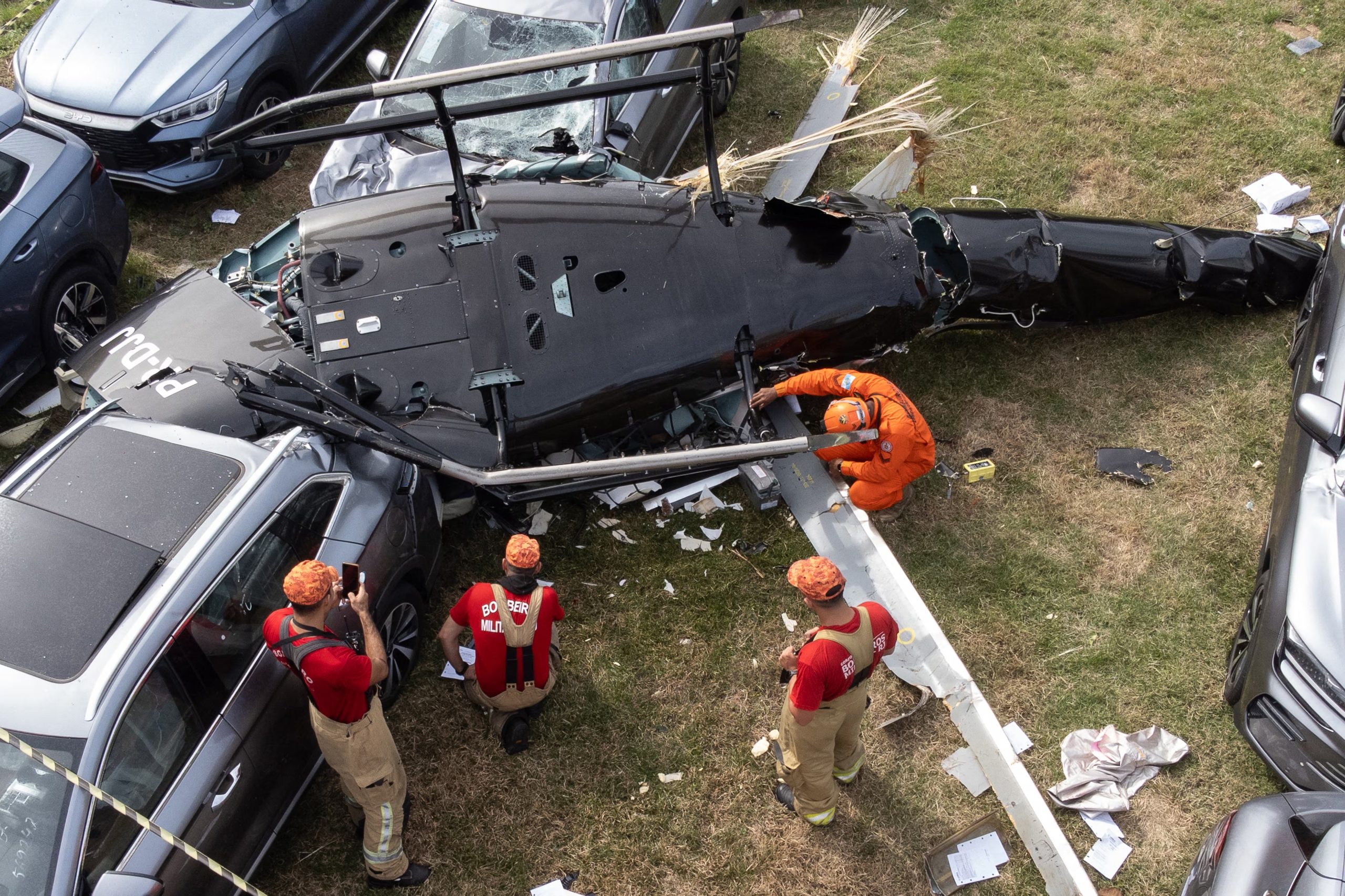 An aerial view shows firefighters working at the site of a helicopter crash in the Recreio dos Bandeirantes neighbourhood in Rio de Janeiro, Brazil, on June 14, 2026. At least six people died in Brazil on June 14 after two helicopters crashed in western Rio de Janeiro, after a suspected mid-air collision, firefighters said. (Photo by Tercio TEIXEIRA / AFP)