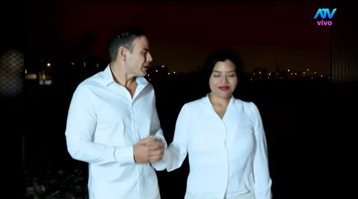 Mark Vito y Leslie Echevarría caminan juntos por la noche, vestidos de blanco, tras su boda ancestral.