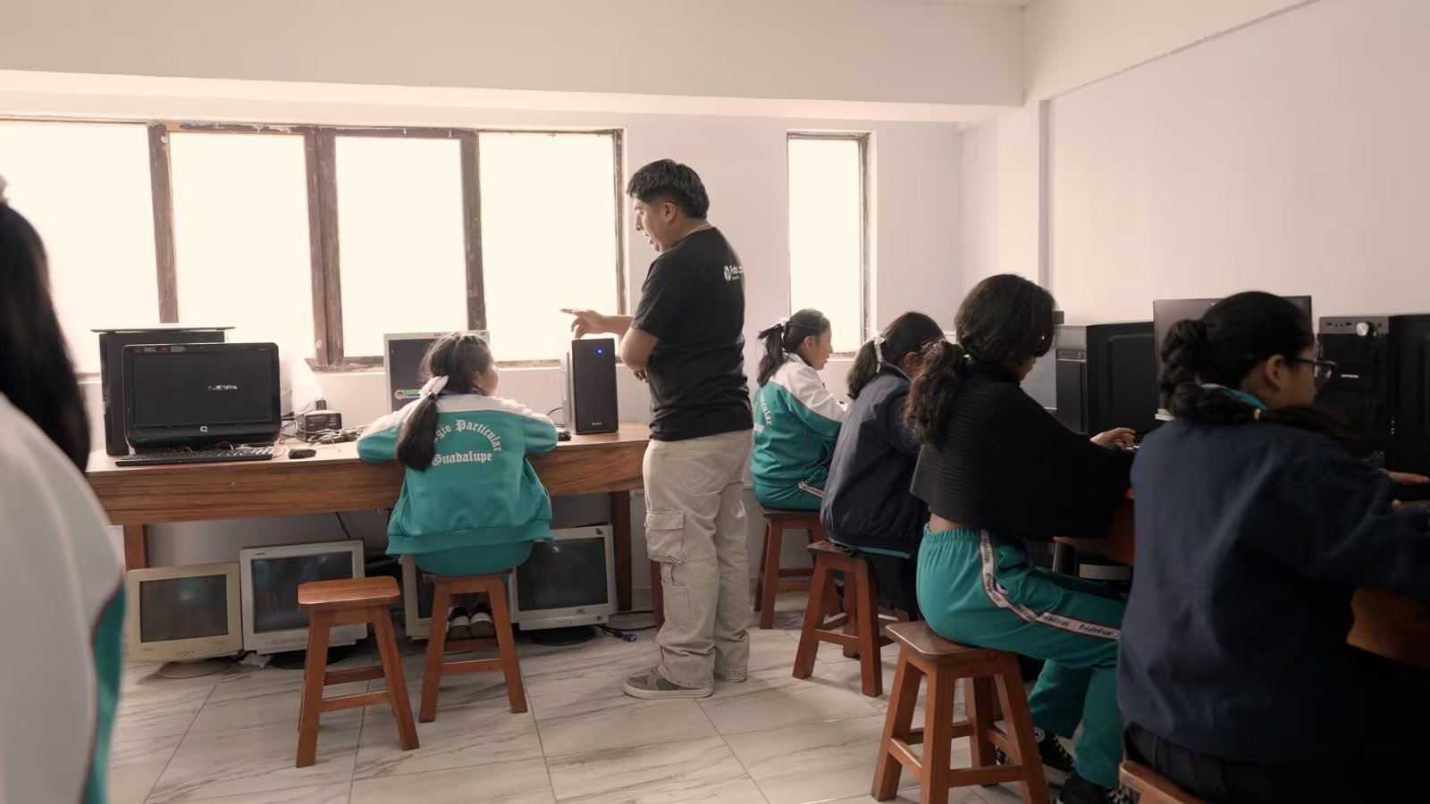 Un profesor supervisa a estudiantes de primaria mientras usan computadoras para jugar Du.Math, un videojuego peruano diseñado para mejorar el aprendizaje de las matemáticas en las aulas.