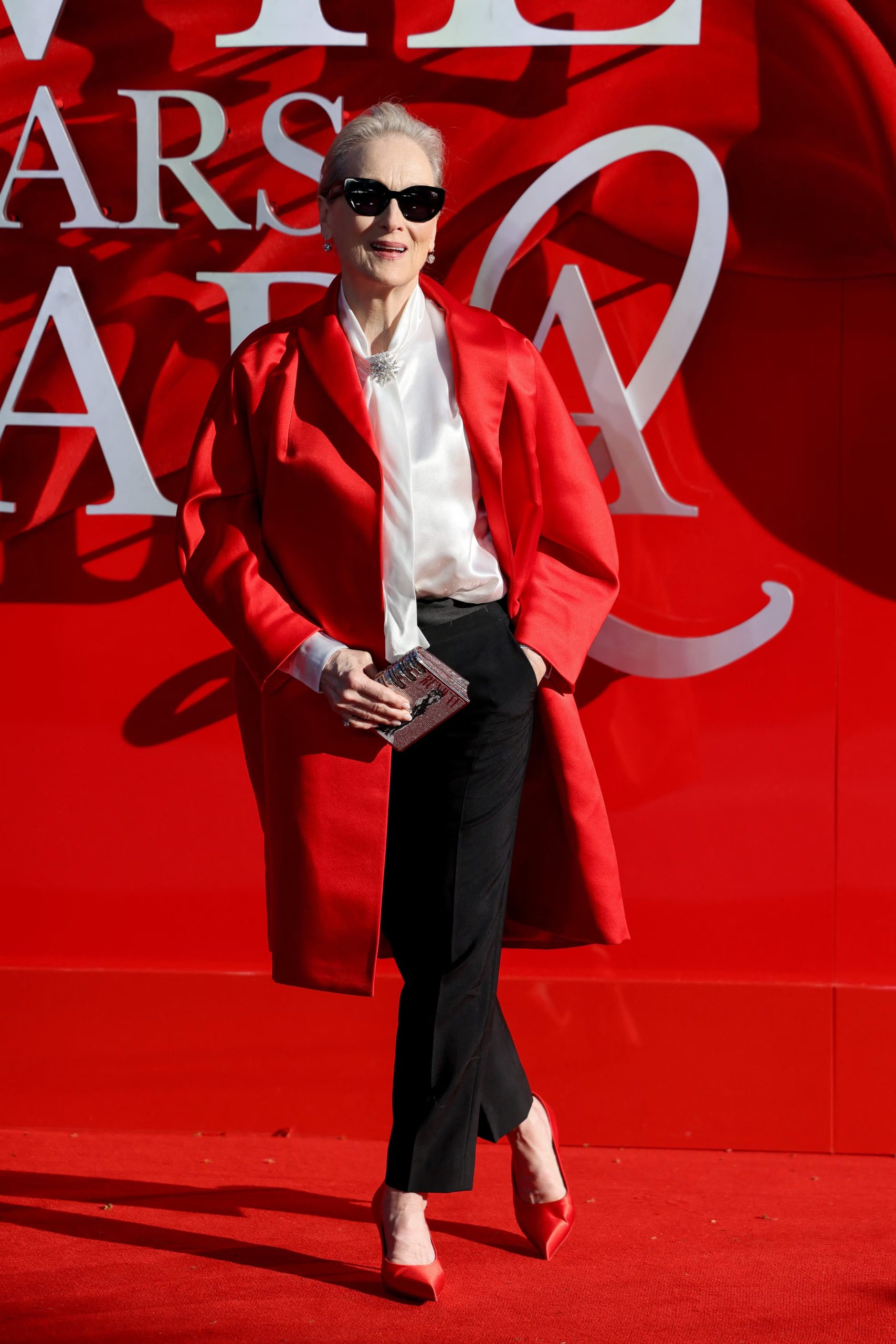 Abrigo rojo satinado oversize, lazo de seda blanco y accesorios oscuros para contraste (REUTERS/Jack Taylor)