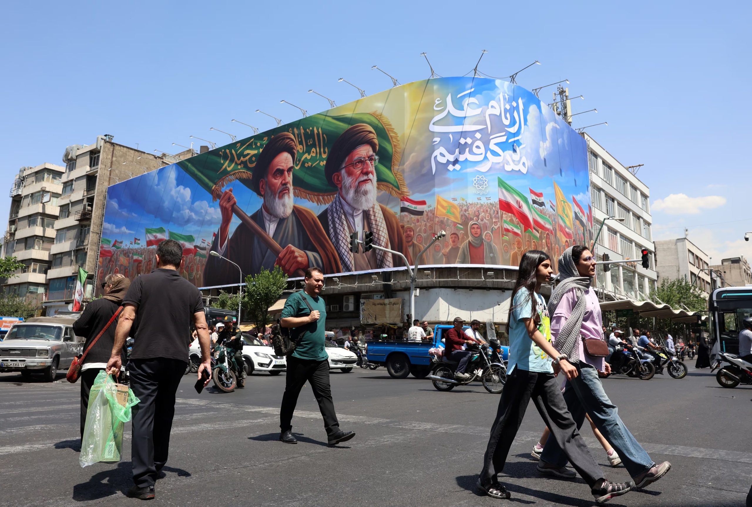Ciudadanos iraníes pasan junto a una gran valla publicitaria en Teherán (EFE/EPA/ABEDIN TAHERKENAREH)