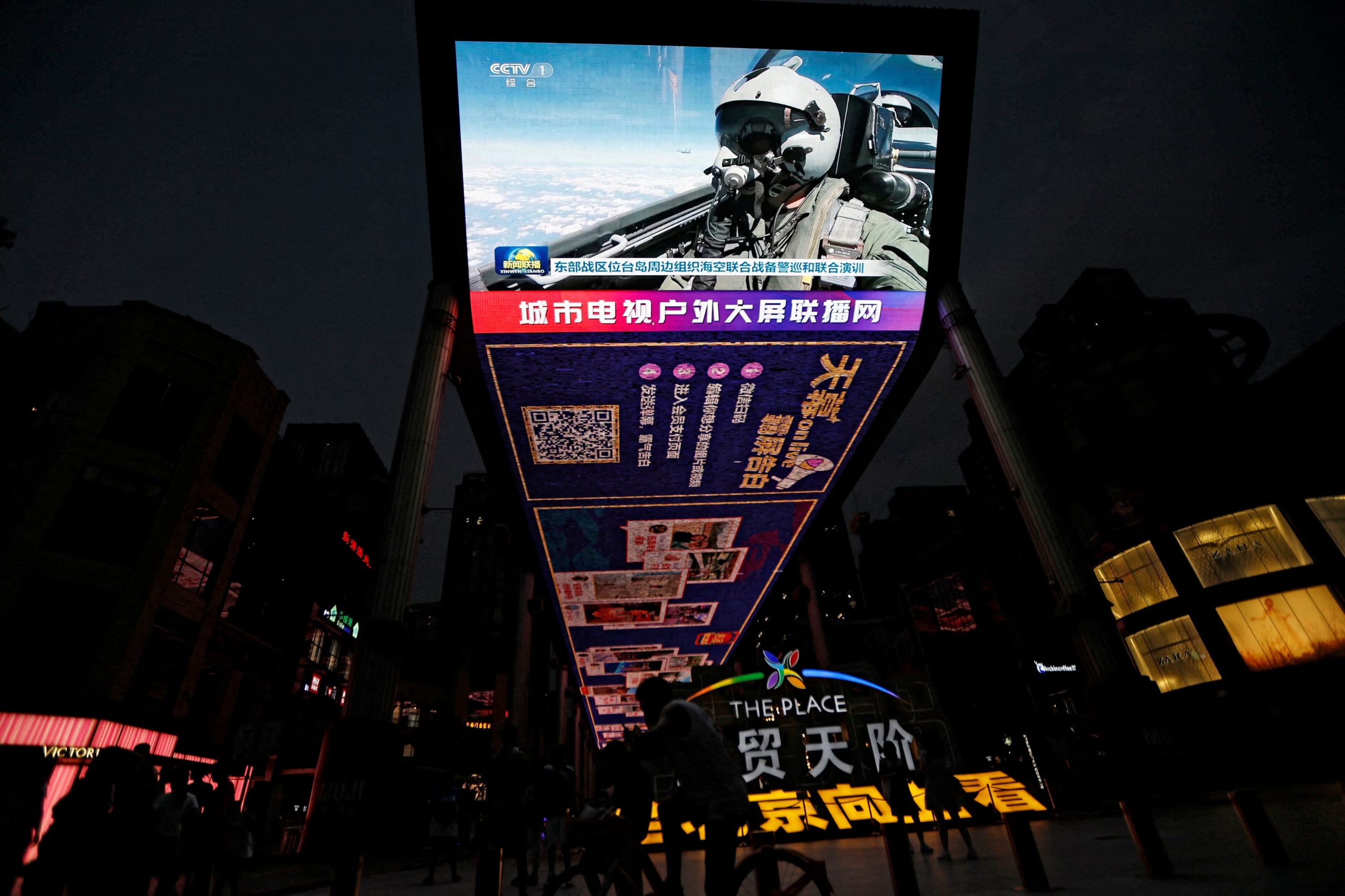 Una pantalla transmite imágenes de noticias de una aeronave de la Fuerza Aérea participando en ejercicios militares del Comando del Teatro Oriental del Ejército Popular de Liberación (EPL) de China alrededor de Taiwán, en una zona comercial de Pekín, China, el 19 de agosto de 2023 (Reuters)