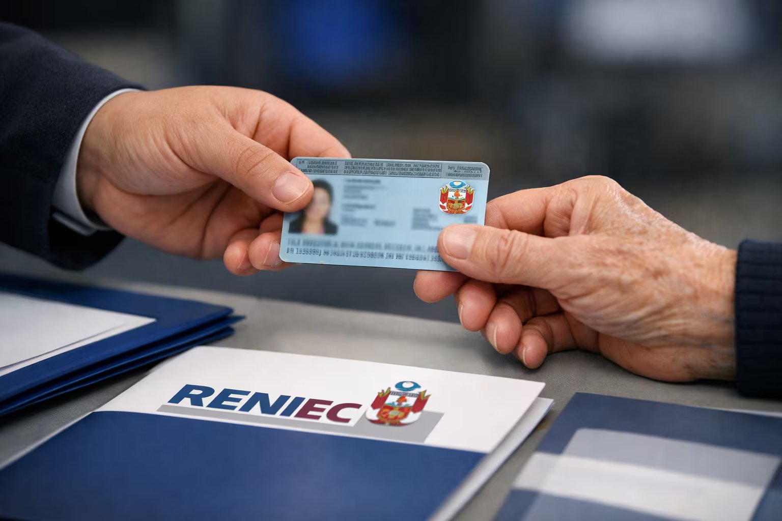 Una mano entrega un Documento Nacional de Identidad (DNI) peruano con el escudo nacional visible a otra, sobre una mesa con material informativo de Reniec, simbolizando el acceso a la identidad ciudadana. (Imagen Ilustrativa Infobae)