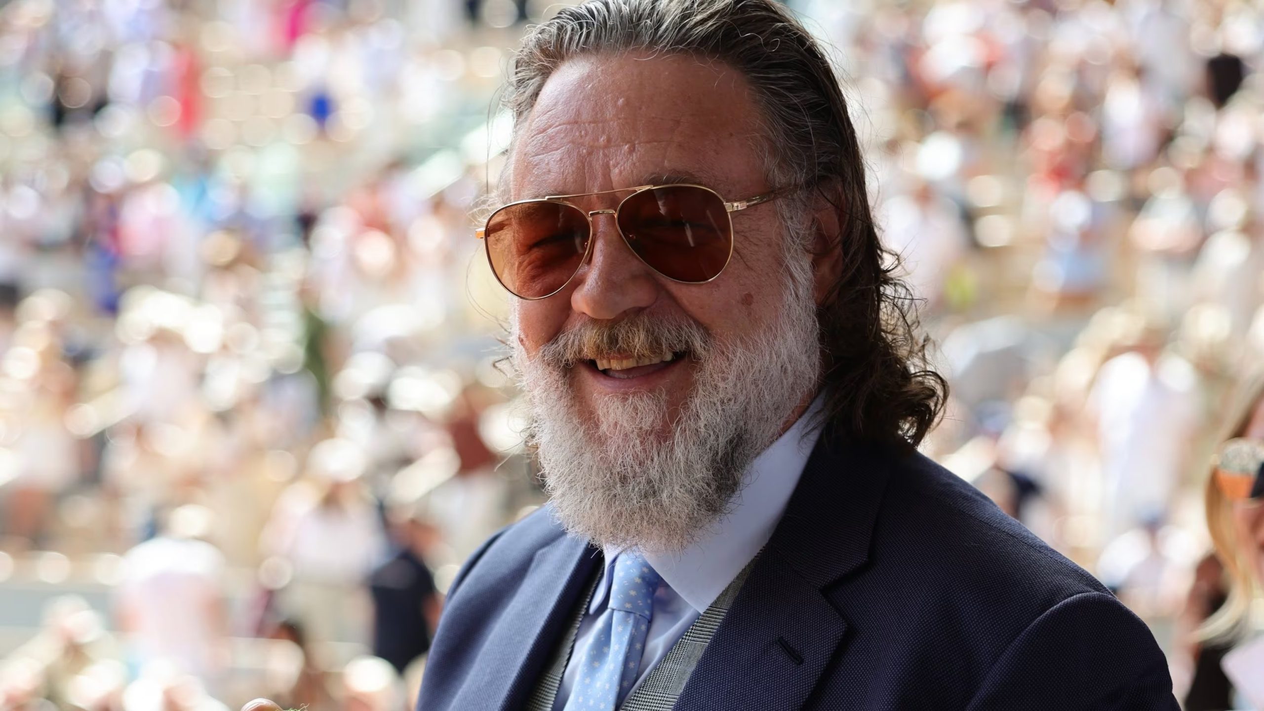El actor Russell Crowe, conocido por sus papeles en cine, posa sonriente con una pelota de tenis que atrapó en pleno partido durante su asistencia al torneo de Roland Garros. (Roland Garros)