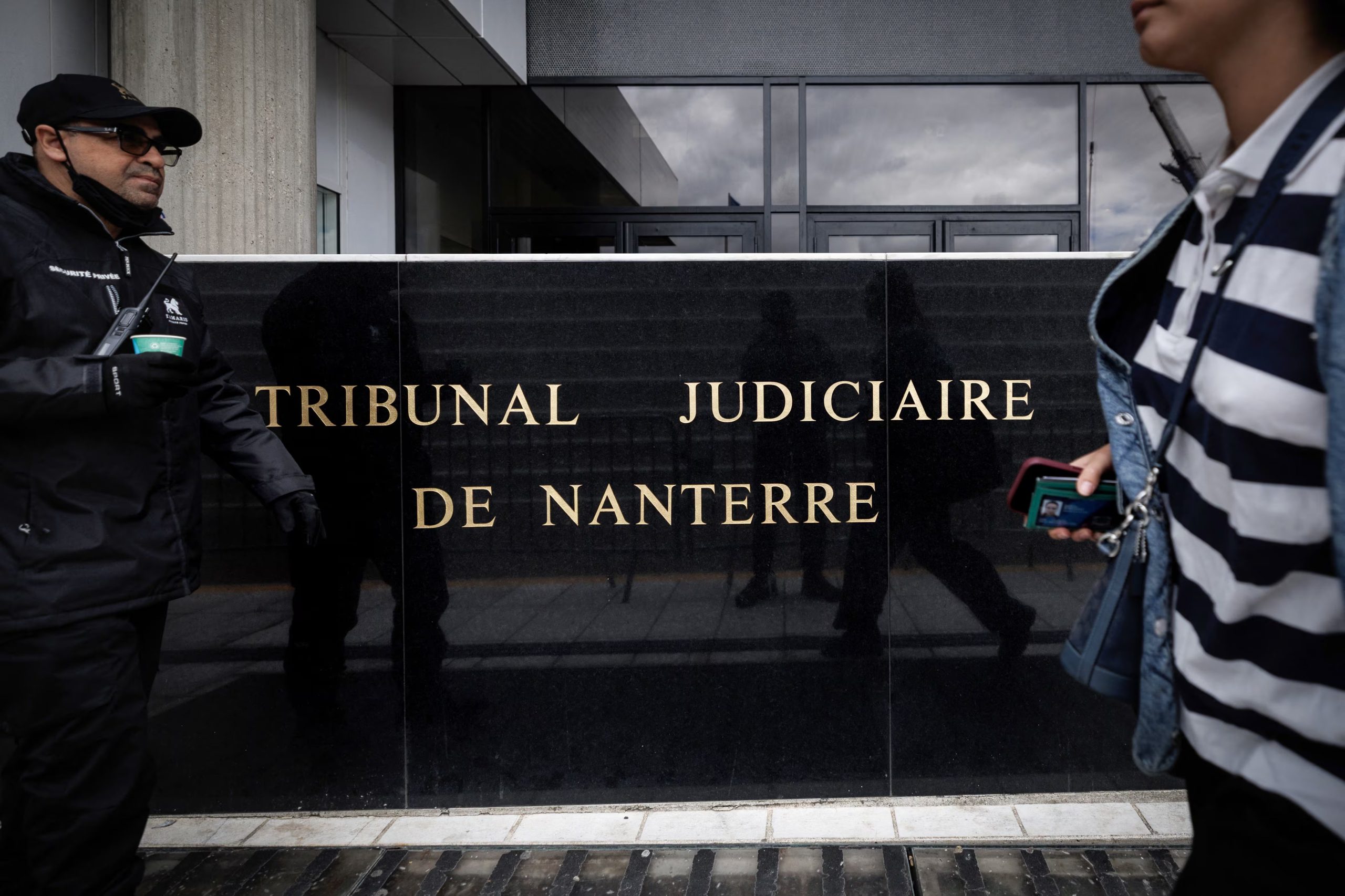A security staff stands as a person passes by the entrance plate of the Nanterre judiciary courthouse (Tribunal Judiciaire de Nanterre) where French singer and actor Patrick Bruel was brought before a judge after prosecutors said they had requested him to be charged and placed in pre-trial detention over nine allegations of sexual abuse including rape and sexual assault, in the northwestern Paris suburb of Nanterre, on June 10, 2026. The 67-year-old, a major figure in French pop culture with multiple top-selling albums and dozens of film appearances, has denied any wrongdoing. He is the latest top French celebrity to face investigators in the wake of the #MeToo movement, after film legend Gerard Depardieu was handed a suspended 18-month prison sentence last year for sexually assaulting two women on a film set. (Photo by SIMON WOHLFAHRT / AFP)