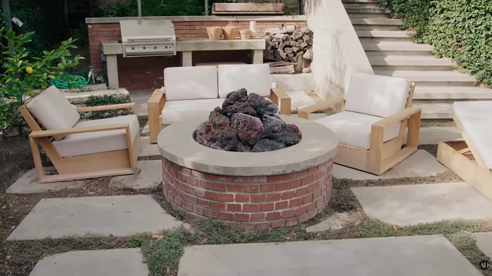 El exterior incluye pileta y un fogón circular de ladrillo visto con piedras volcánicas. (Youtube/AD Magazine)