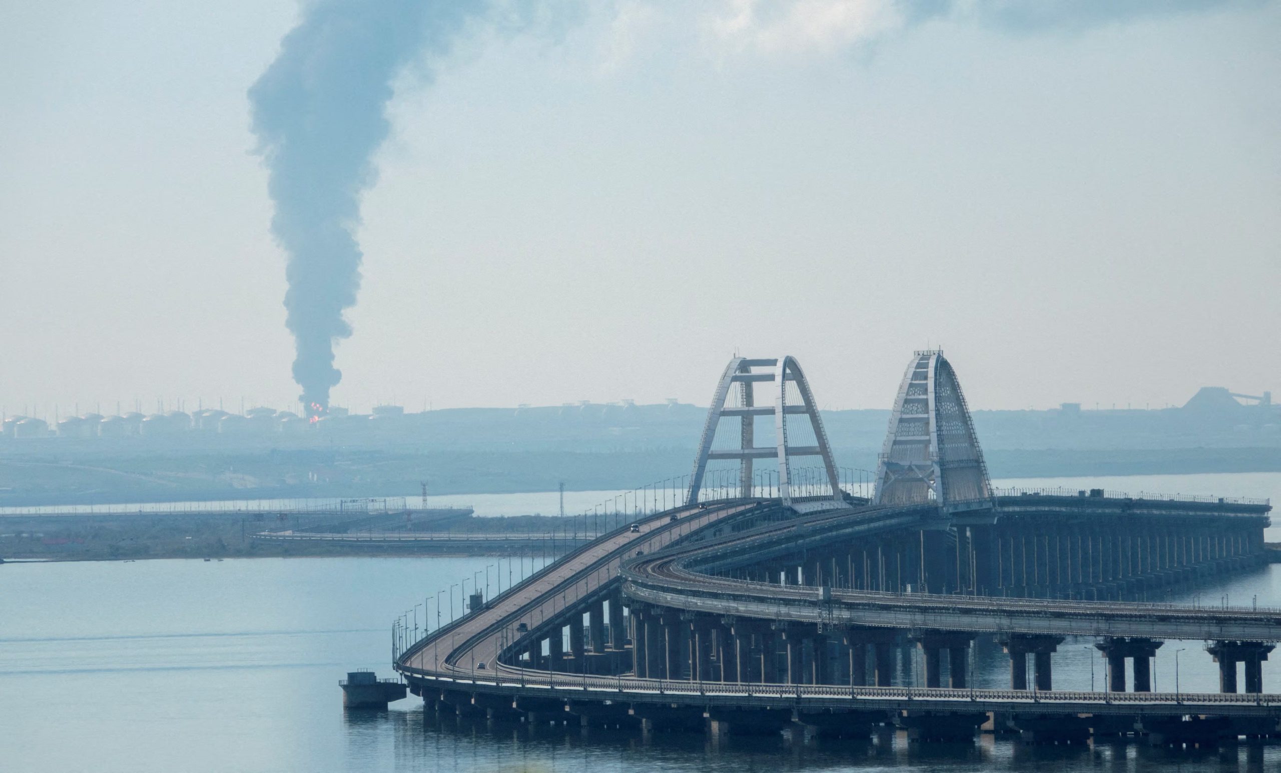 Vista a través del estrecho de Kerch, donde se observa humo sobre un depósito de combustible cerca del puente de Crimea, en el pueblo de Volna, región rusa de Krasnodar, una infraestructura clave para el suministro de la península que volvió a ser blanco de ataques ucranianos. (REUTERS/Stringer, archivo)