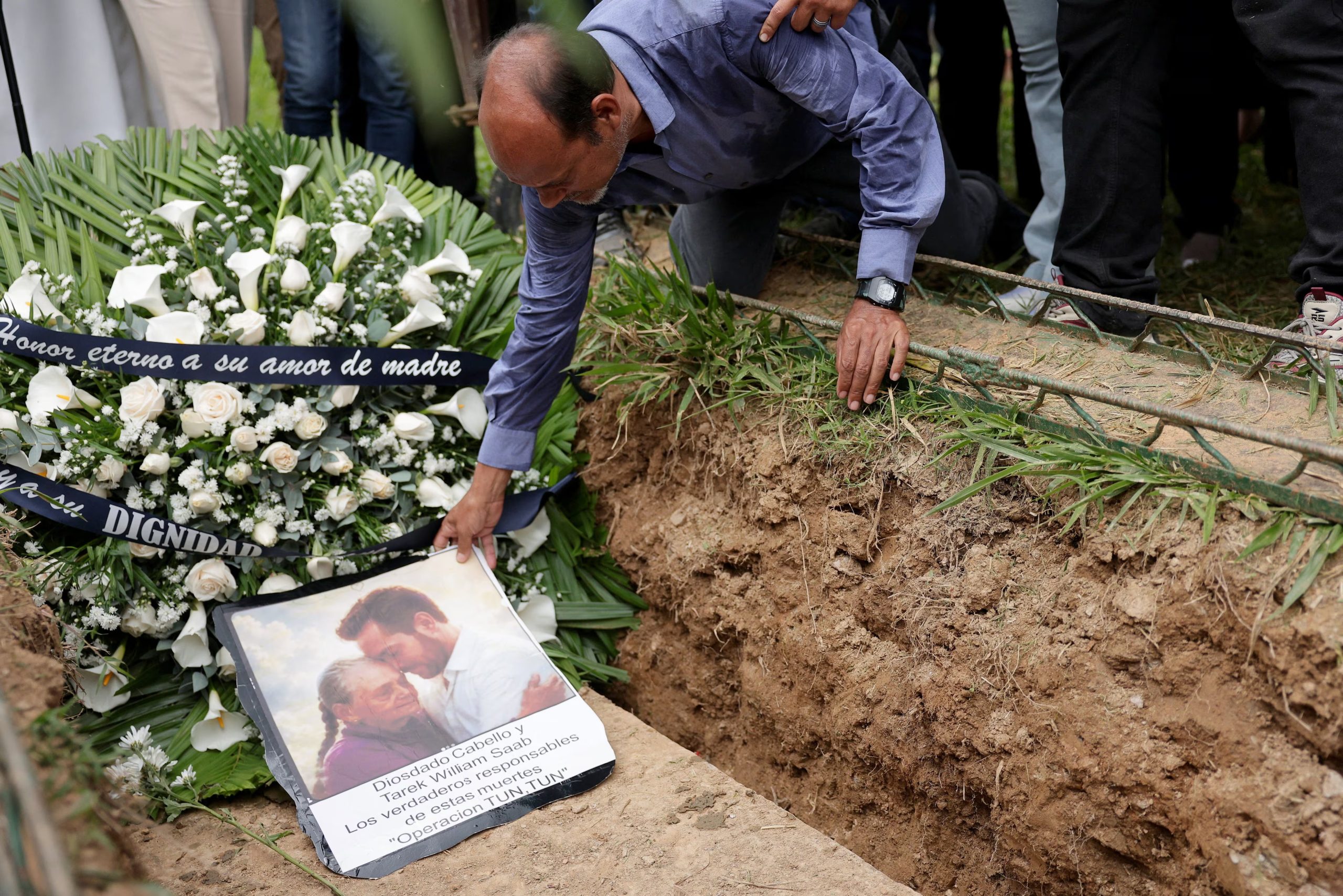 Gabriel Quero coloca un retrato generado por IA de su madre, Carmen Navas, y de su hermano, Víctor Quero, en el funeral de Navas (REUTERS/Gaby Oraa)
