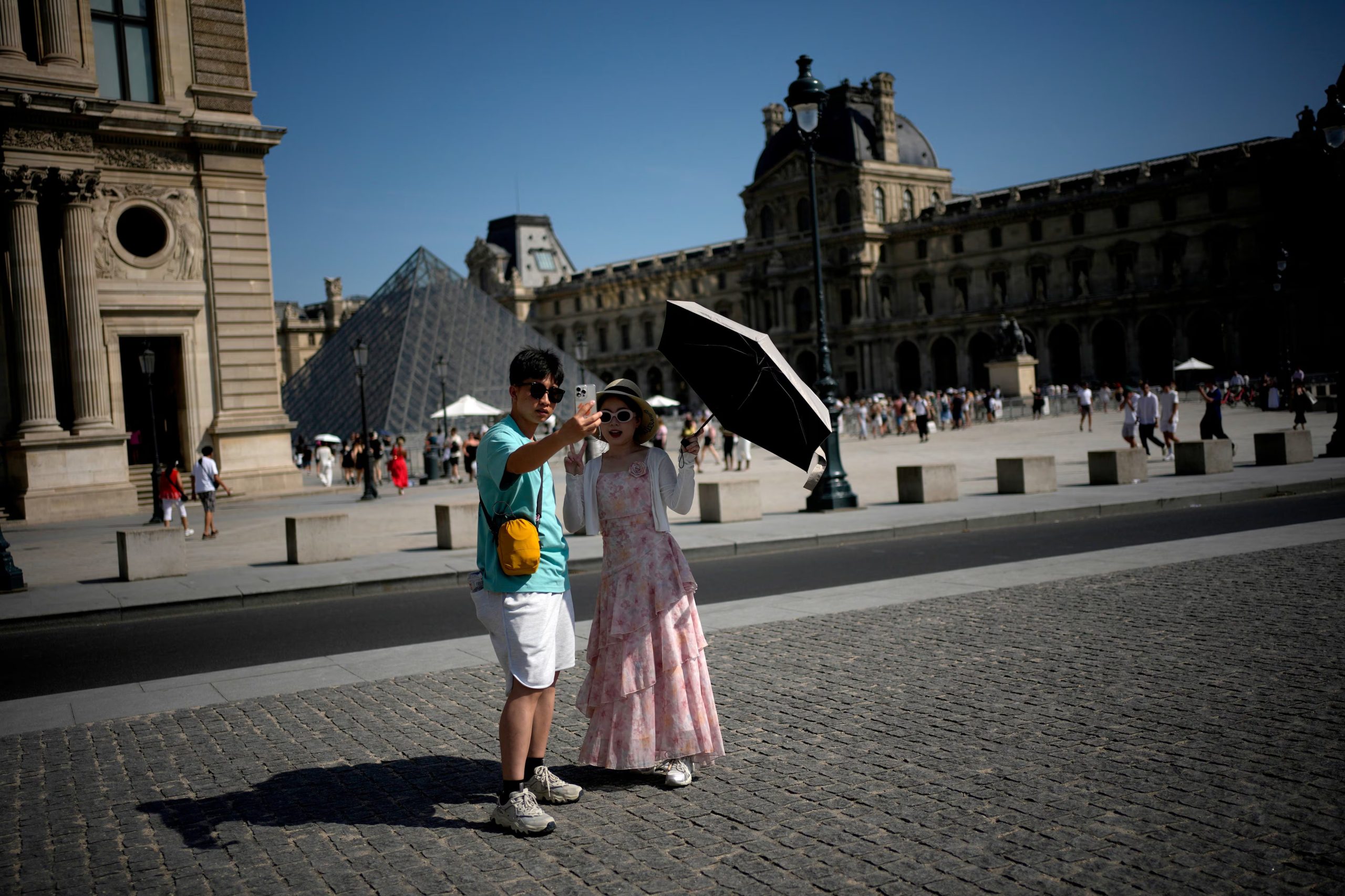 Turistas usan un paraguas para protegerse del sol en París, el 22 de junio de 2026, durante la intensa ola de calor que afecta a Francia. (Foto AP/Christophe Ena)