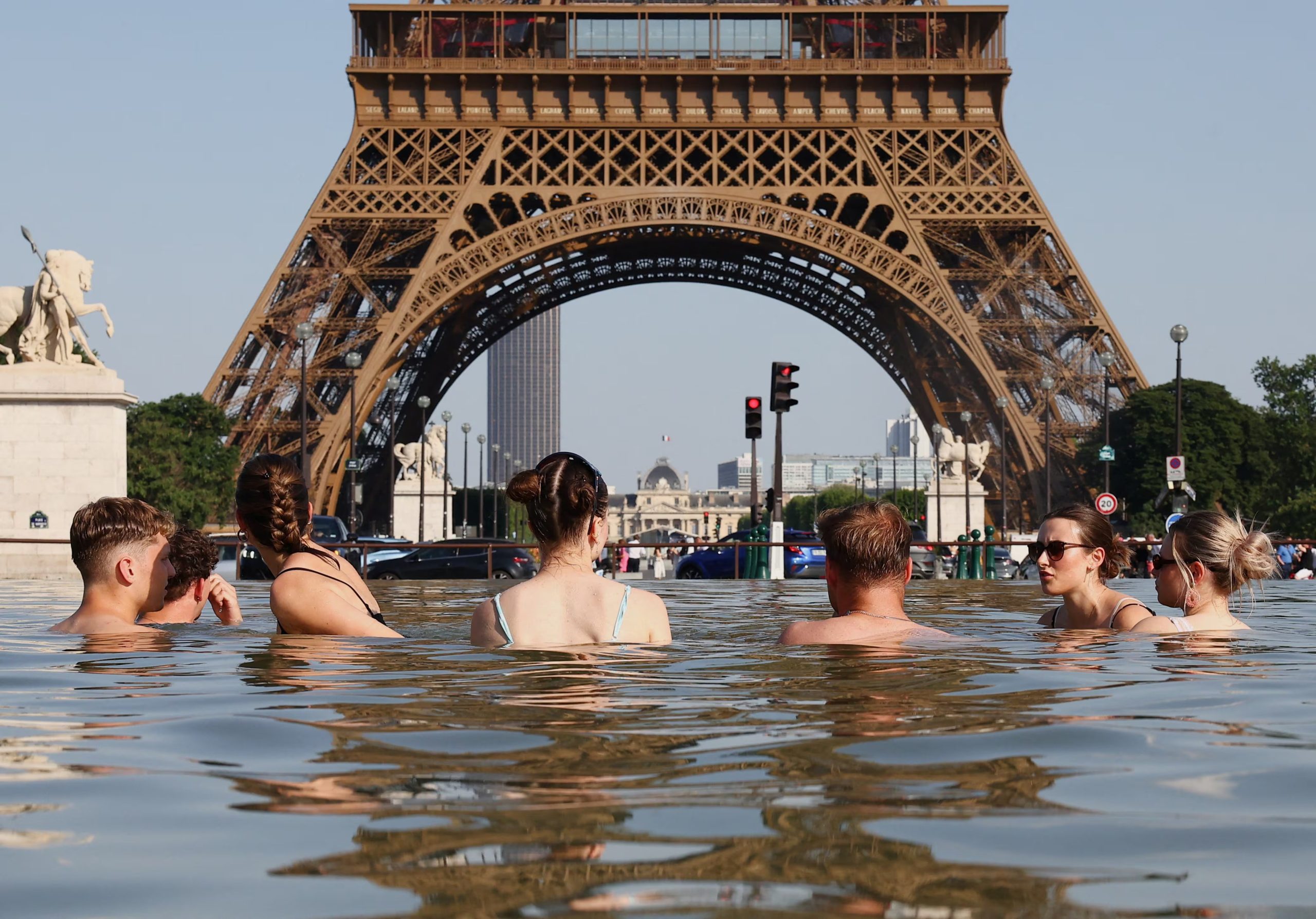 Gente se refresca en la fuente del Trocadero, cerca de la Torre Eiffel en París, el 22 de junio de 2026, en medio de la ola de calor en Francia. (Foto Reuters/Abdul Saboor)