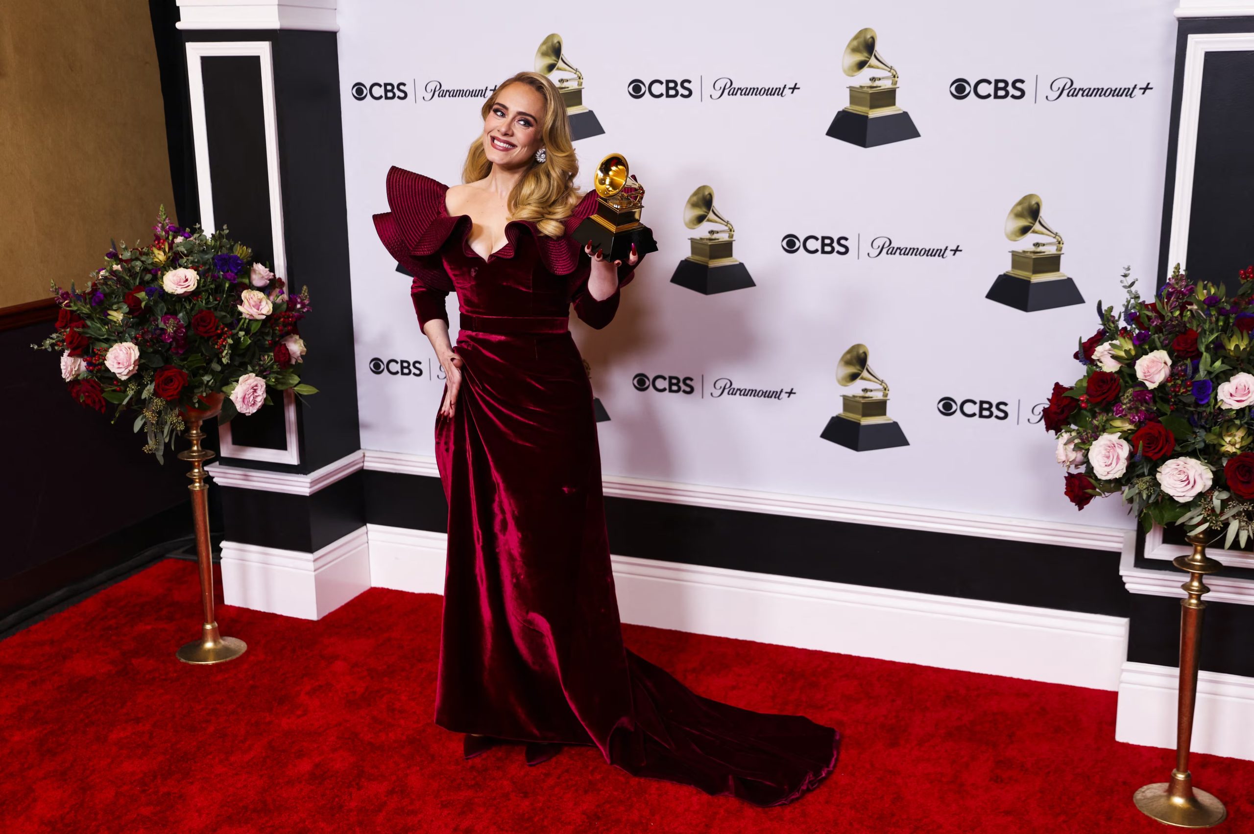 Adele apuesta por un vestido largo de terciopelo burdeos con escote en V y volantes estructurados en los hombros para una entrega de premios (REUTERS/Mike Blake)