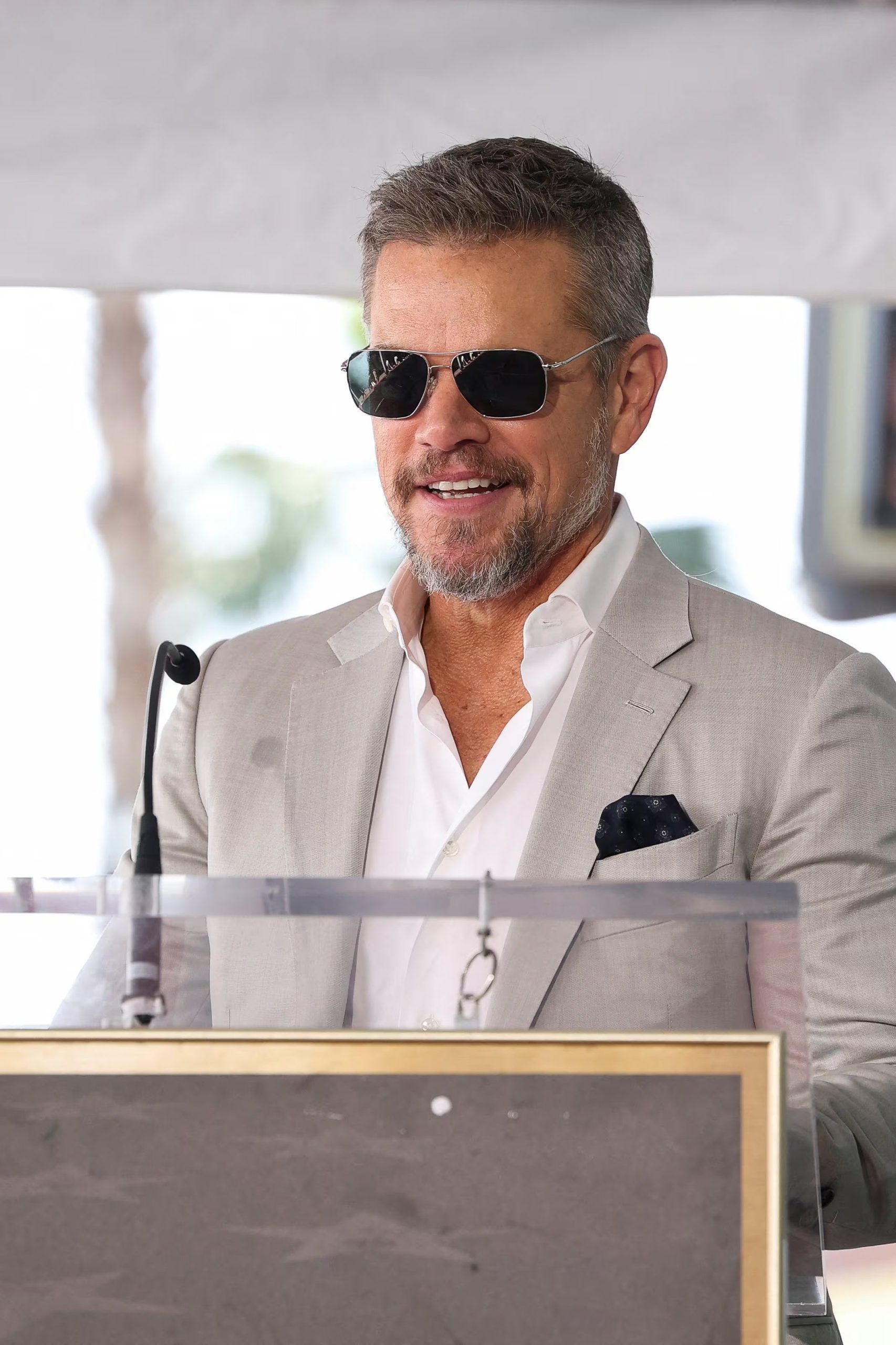 Traje gris claro sin corbata y con camisa abierta, más pañuelo azul oscuro y gafas metálicas, la versión relajada del actor en el Camino de la Fama (REUTERS/Mario Anzuoni)