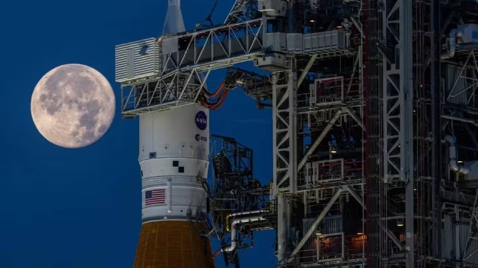 La luna llena se eleva sobre el cohete del programa Artemis II en la Plataforma de Lanzamiento 39B del Centro Espacial Kennedy, preparándose para una futura misión a la Luna. (Ben Smegelsky / NASA)