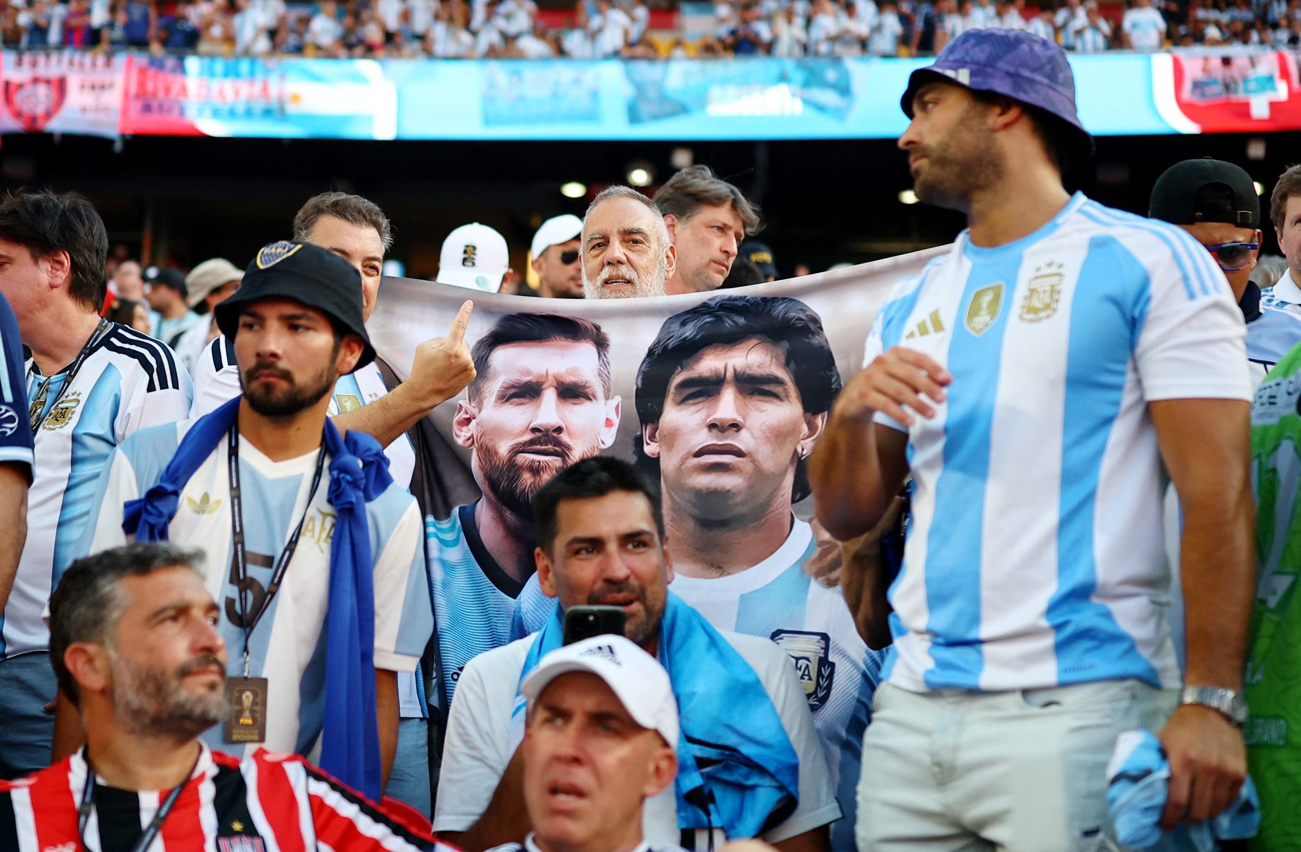 Un fan con una bandera con los rostros de Messi y Maradona