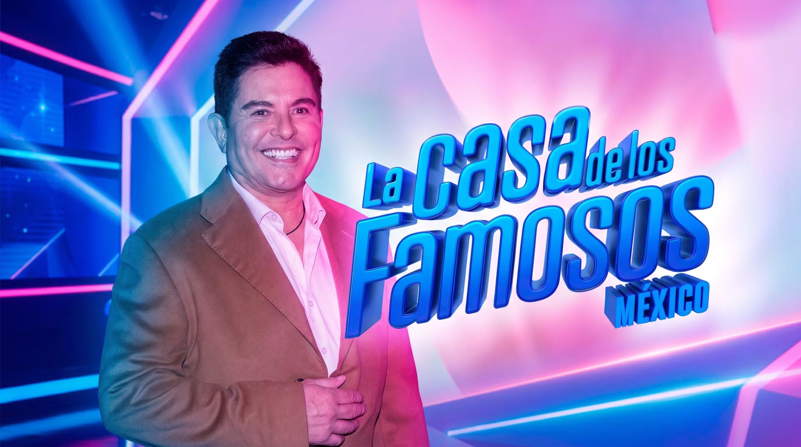 El presentador Ernesto Laguardia posa sonriente junto al logo del programa La Casa de los Famosos México, sobre un fondo de luces de neón azules y rosas. (Imagen Ilustrativa Infobae)