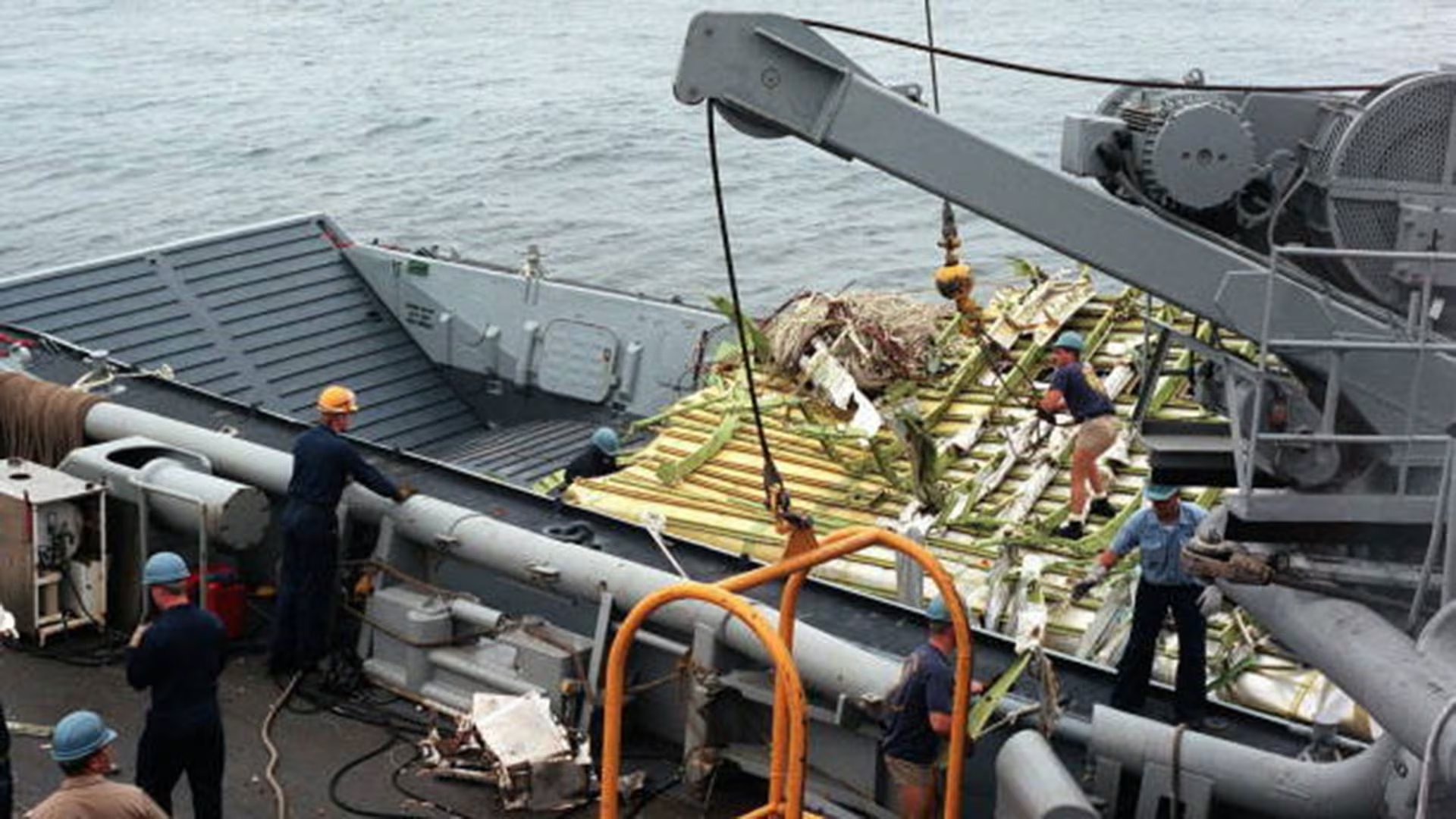 Los restos del fuselaje delantero del vuelo 800 de TWA son transferidos desde el buque de salvamento y recuperación de la Armada a una embarcación de servicio para ser trasladados a tierra firme