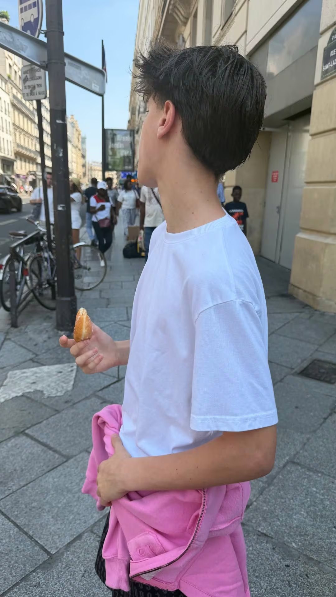 Uno de los hijos de la empresaria recorre las calles del centro de París con un croissant en la mano, cerca de la zona de Saint-Lazare