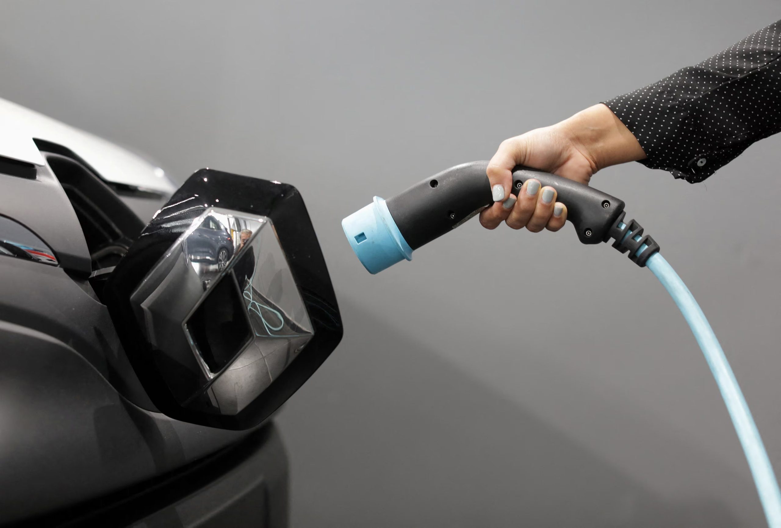 FILE PHOTO: A woman holds a cable to charge up a Renault Kangoo ZE electric utility vehicle at a Renault automobile dealership in Cagnes-Sur-Mer, France, October 22, 2020. Picture taken October 22, 2020. REUTERS/Eric Gaillard/File Photo